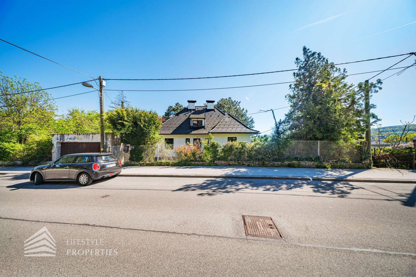 Ansicht des Hauses von der Straße mit geparktem Auto und blauem Himmel.