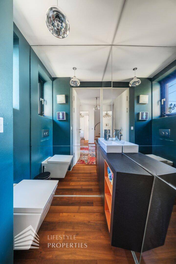 Modernes Badezimmer mit blauen Wänden, Holzboden und minimalistischem Doppelwaschbecken.