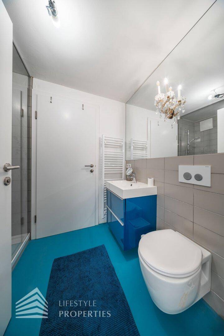 Modernes Badezimmer mit blauen Akzenten, Toilette, Waschbecken und Spiegel.