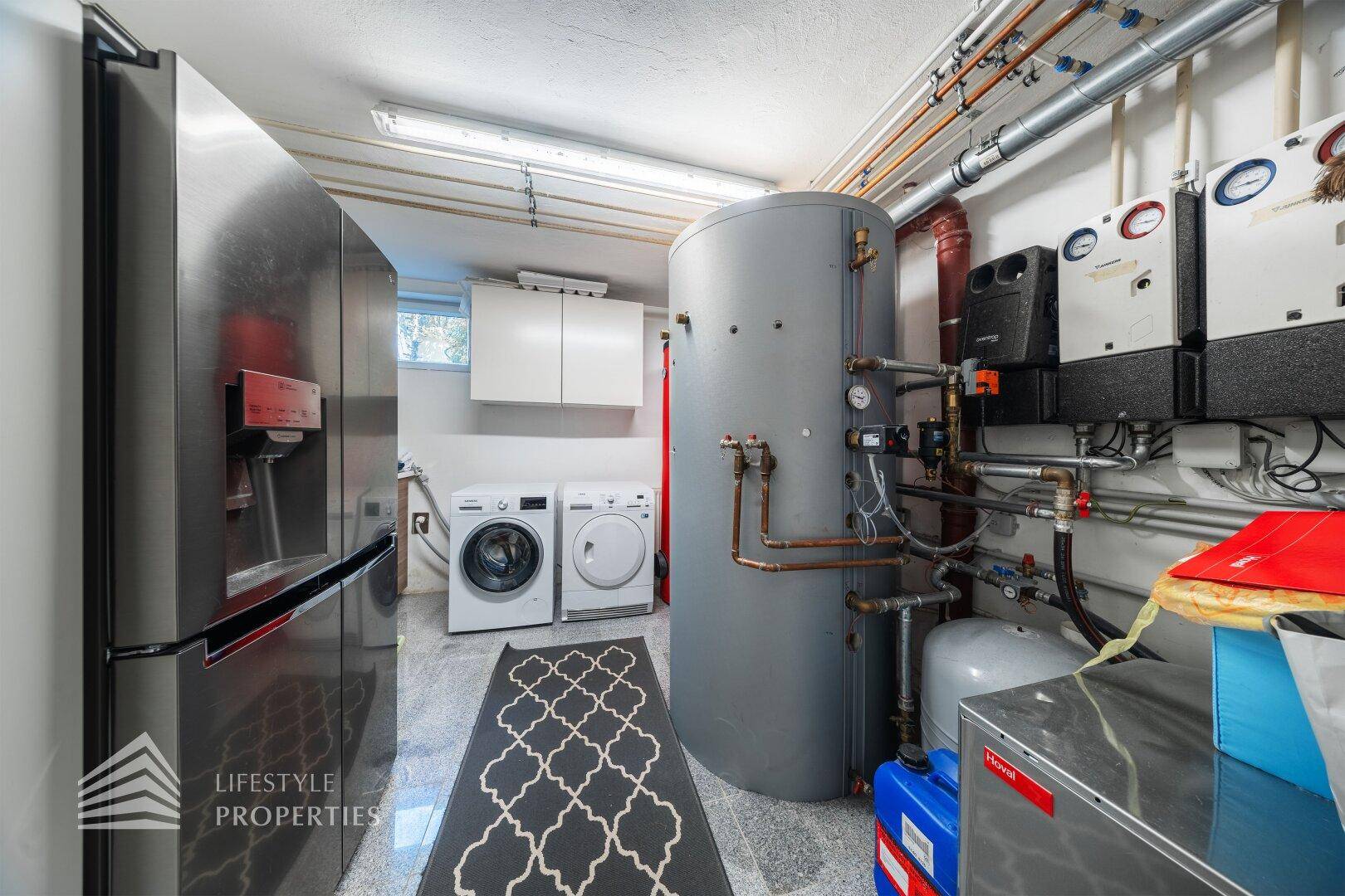 Hauswirtschaftsraum mit Waschmaschine, Trockner, Heizungsanlage und Warmwasserspeicher.