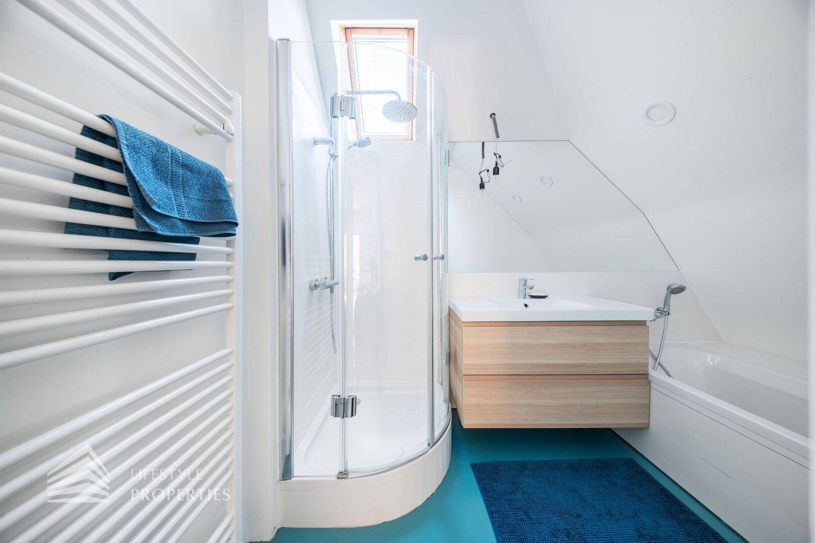 Modernes Badezimmer im Dachgeschoss mit Dusche, Waschbecken und beheiztem Handtuchhalter.