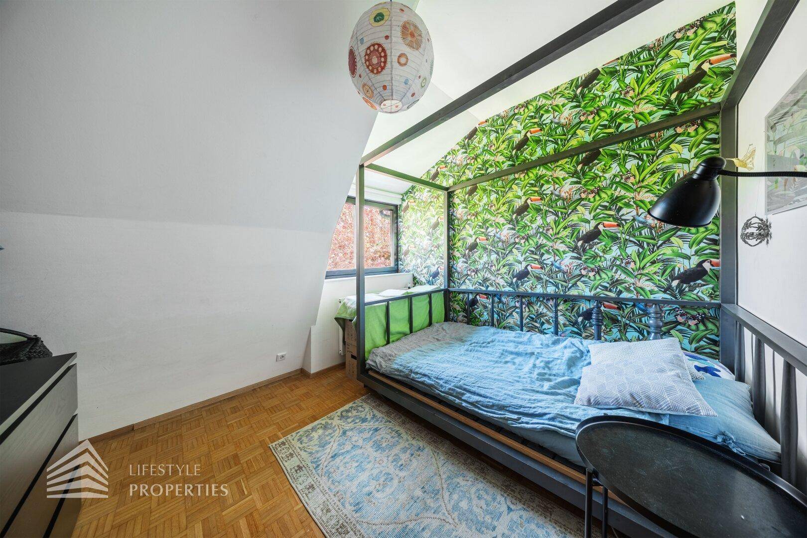 Schlafzimmer mit auffälliger Dschungel-Tapete, Himmelbett und Parkettboden.