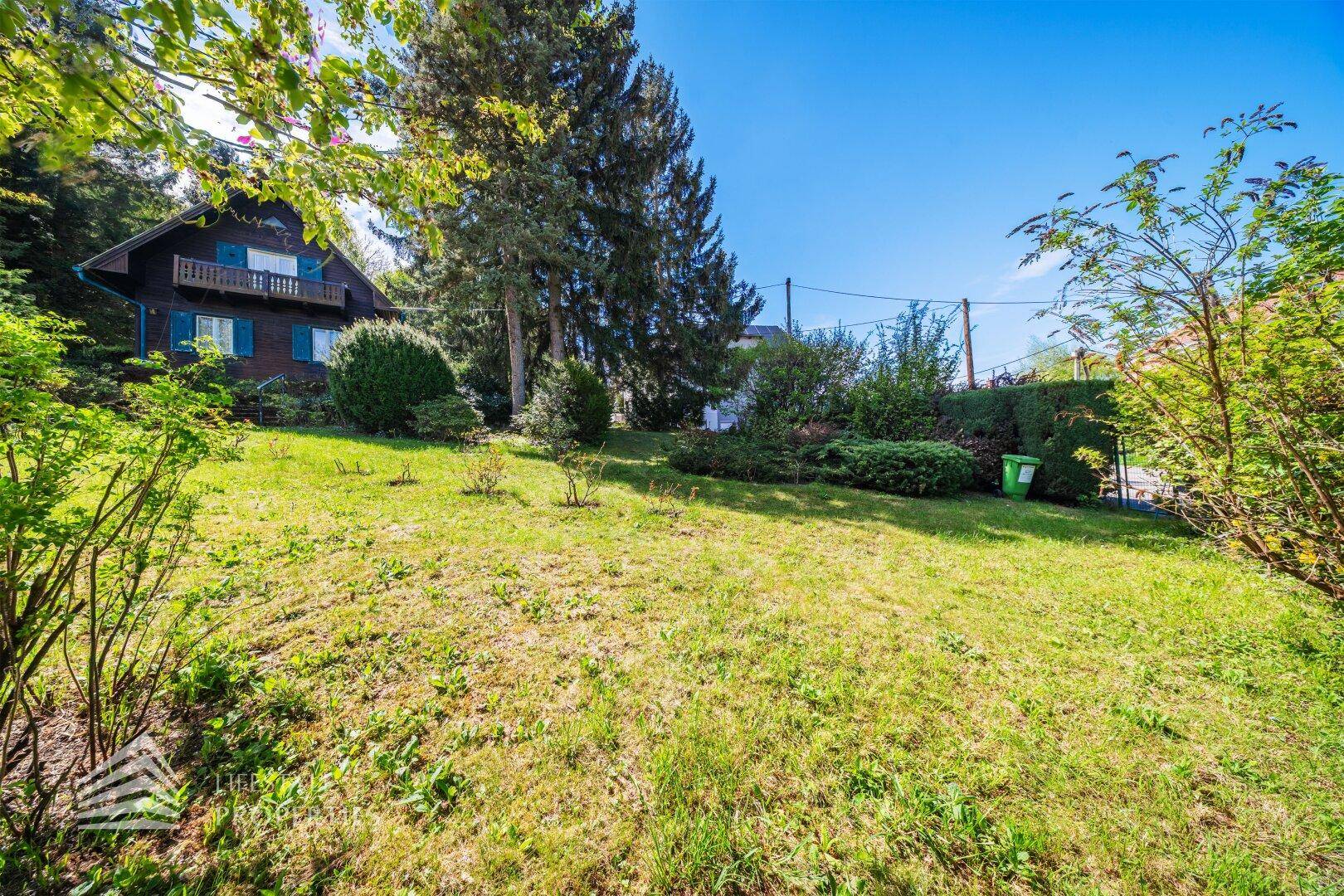 Gepflegter Rasenbereich im Garten mit Blick auf das charmante Holzhaus und die Umgebung.