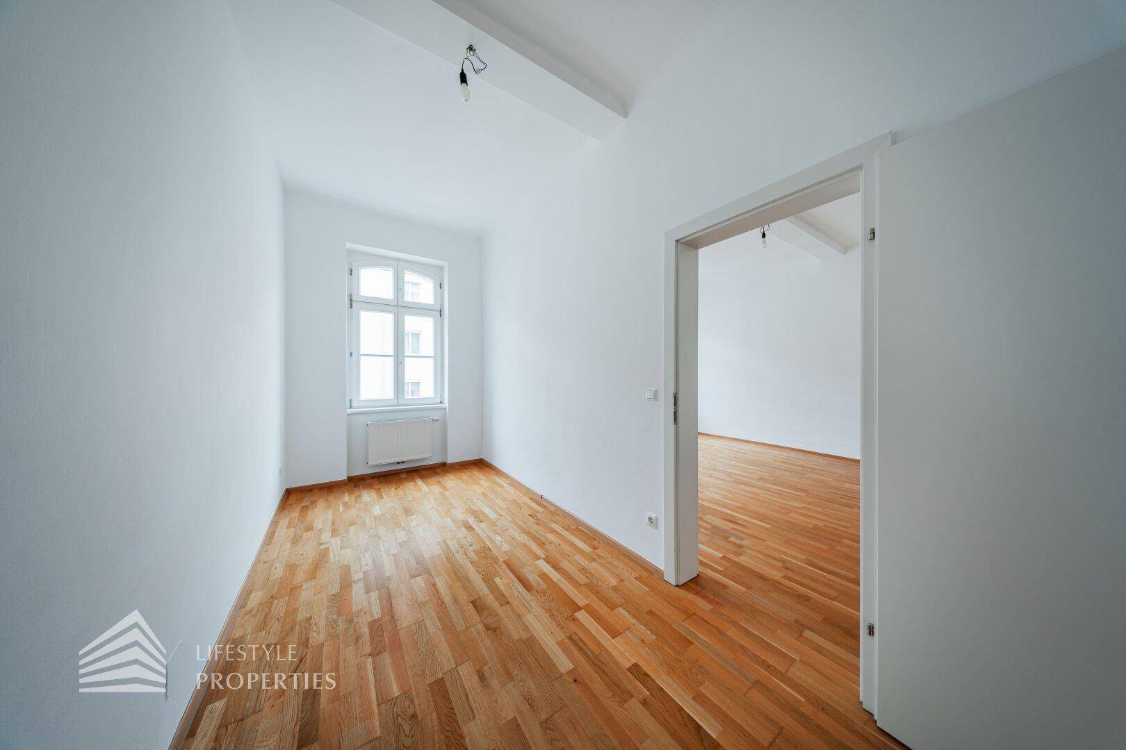 Kleineres Zimmer mit Parkettboden und einem Fenster, ideal als Schlaf- oder Arbeitszimmer.