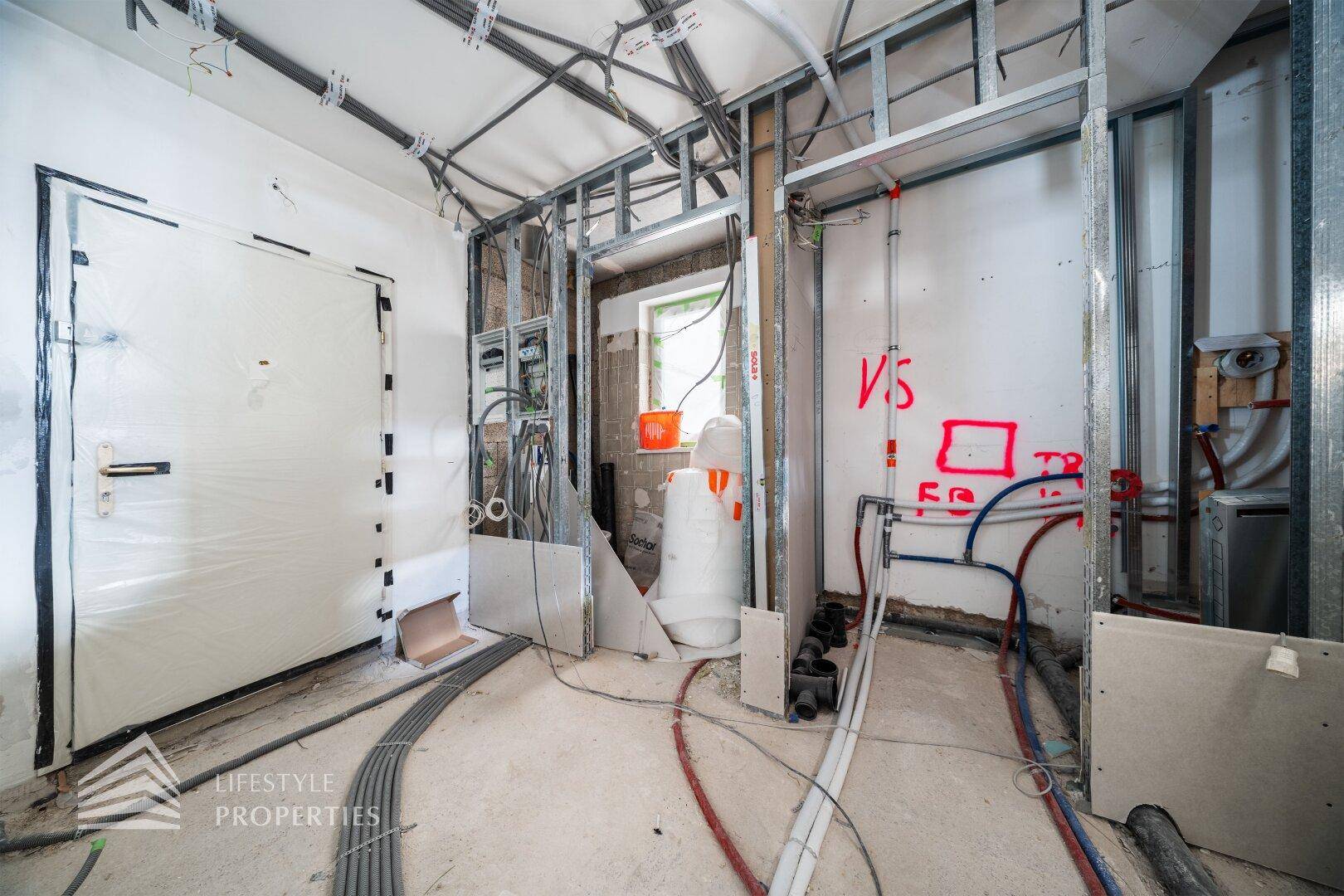 Raum im Rohbau mit Installationen für Sanitär und Elektrik, bereit für den Ausbau.