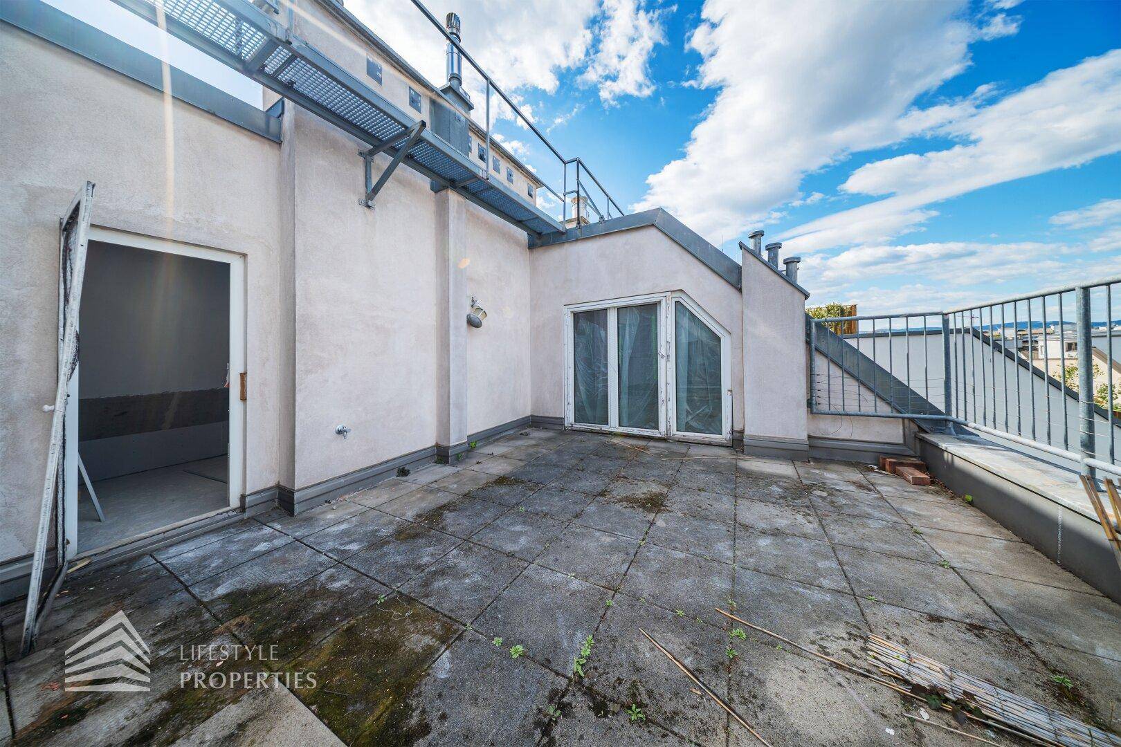 Geräumige Dachterrasse im Rohzustand mit Zugang zum Innenbereich.
