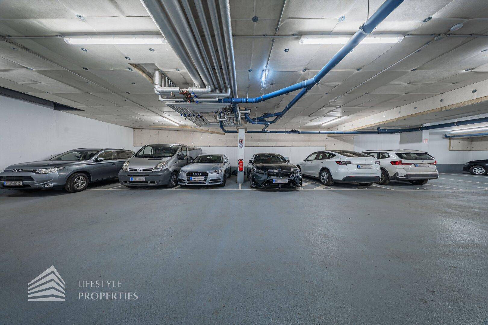 Weitere Ansicht der Tiefgarage mit zahlreichen geparkten Autos und klarer Beschilderung.