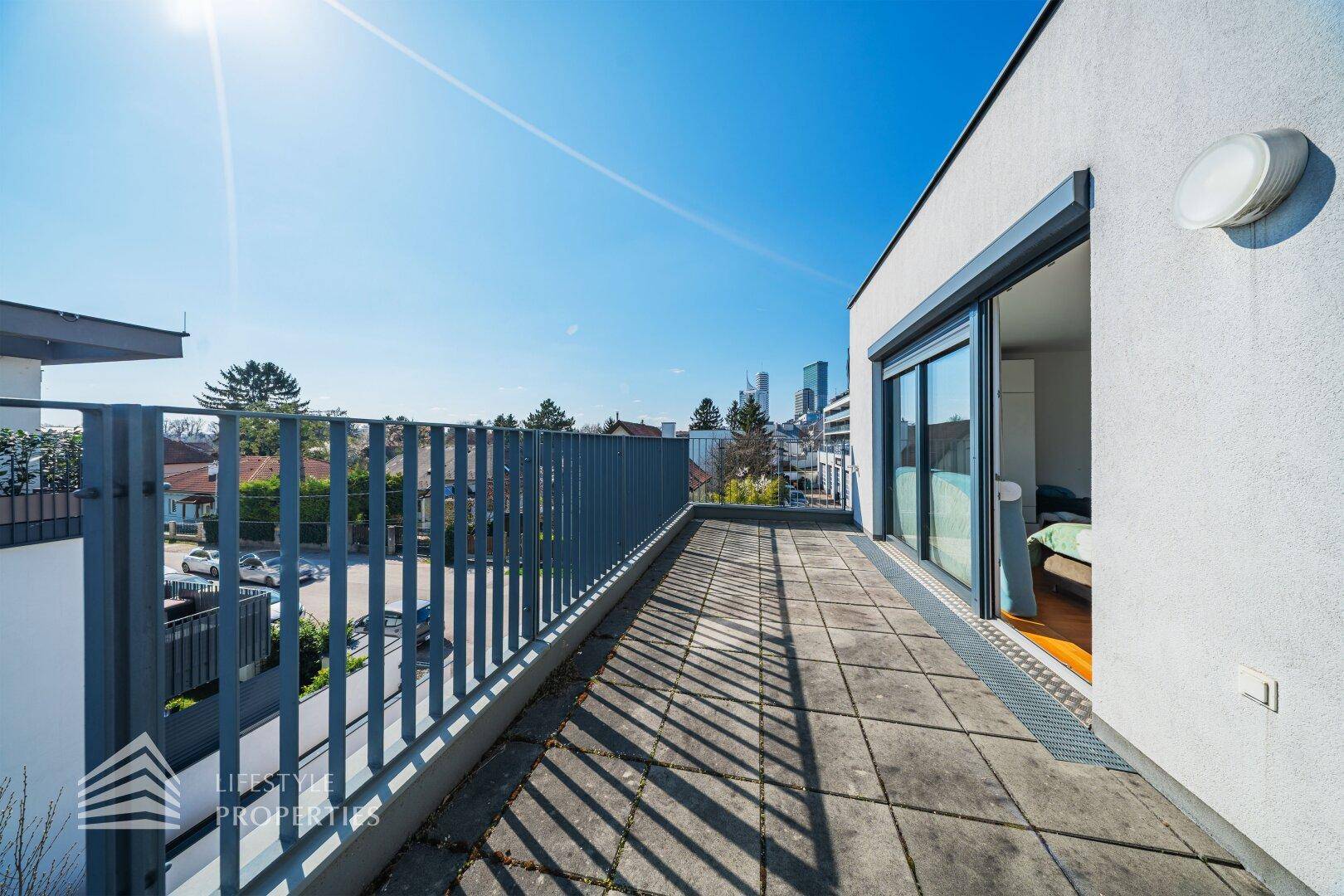 Langer Balkon mit Metallgeländer, der einen weiten Blick über die Nachbarschaft und die Stadt bietet.