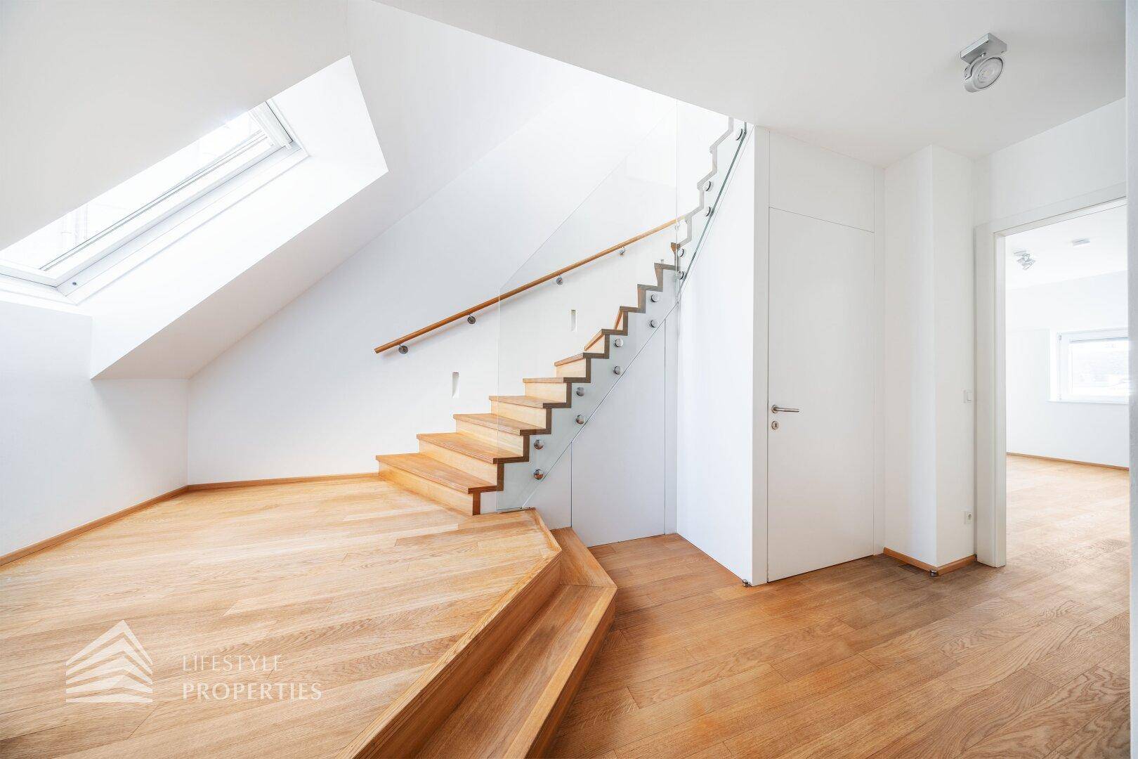 Moderner Flur mit Holztreppe, Glasgeländer und Dachfenster.