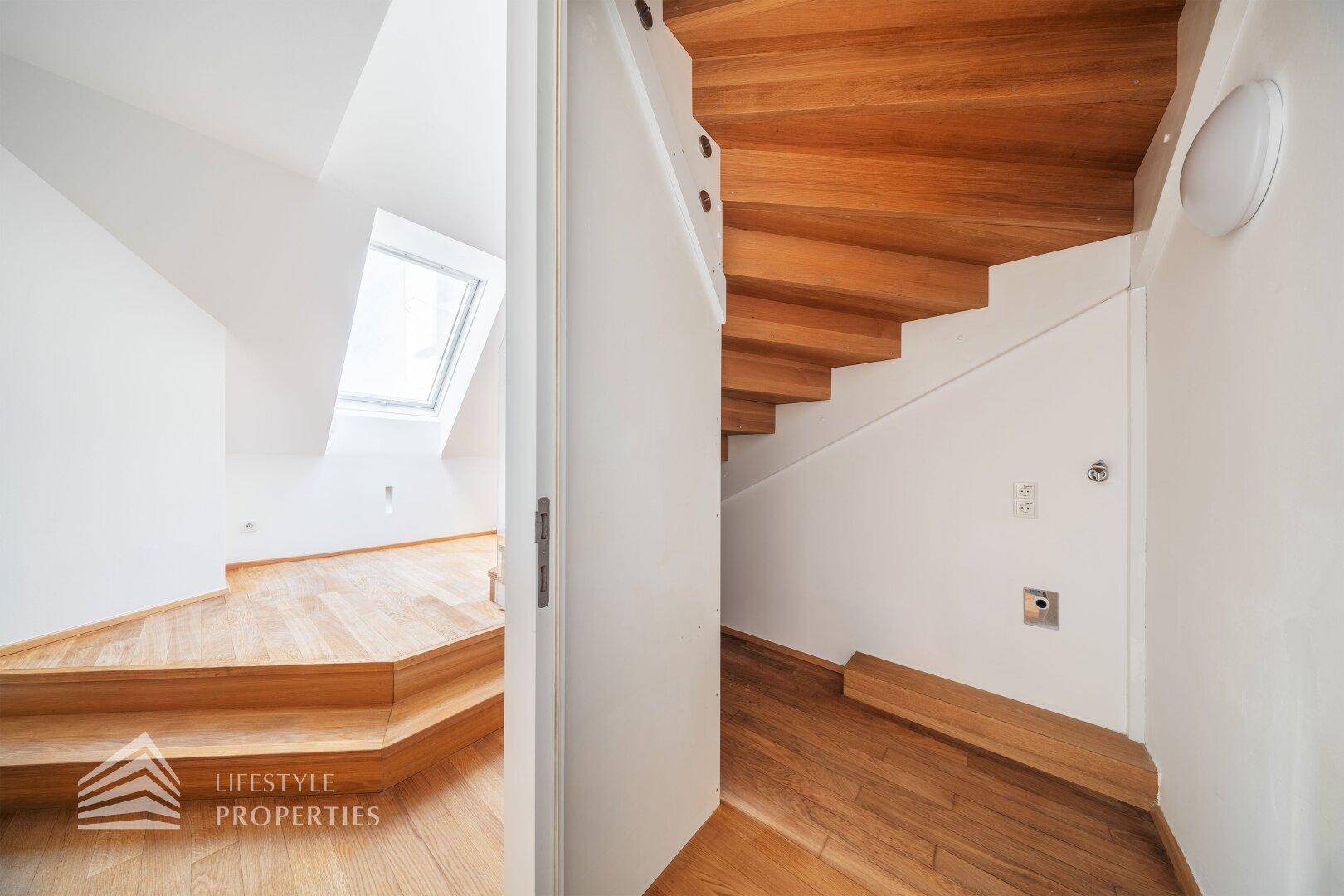 Bereich unter der Treppe mit Holzboden und Zugang zu einem weiteren Raum.