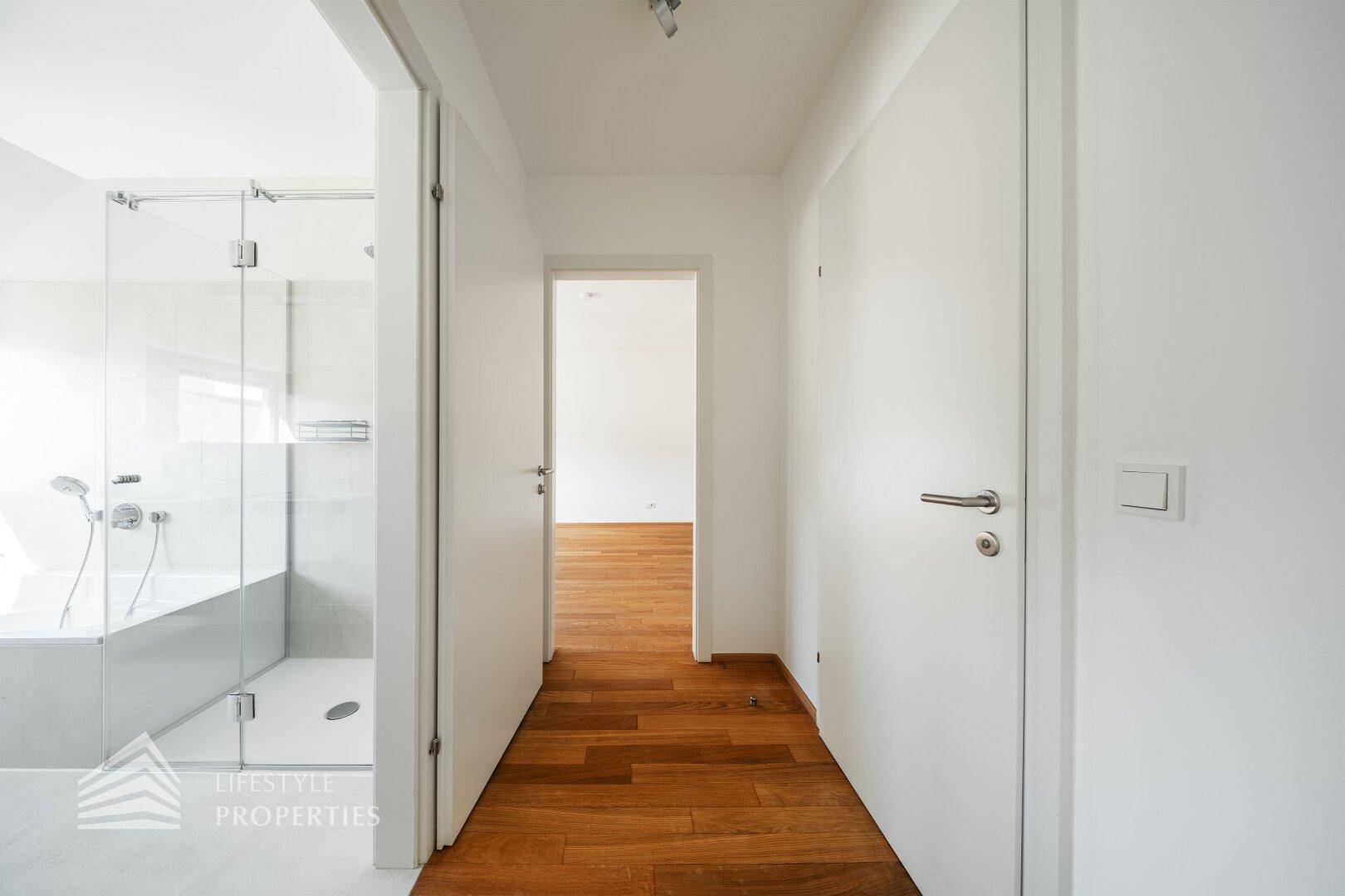 Heller Flur mit Holzboden und Zugang zu mehreren Zimmern und Badezimmer.