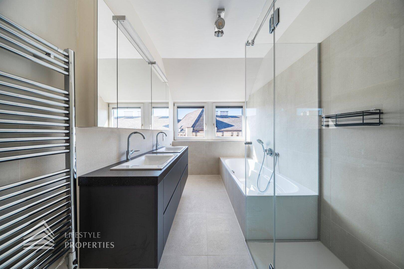 Modernes Badezimmer mit Doppelwaschbecken, Badewanne, Dusche und beheiztem Handtuchhalter.