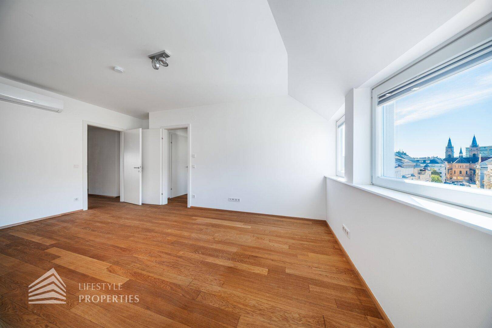 Geräumiges Schlafzimmer mit Holzboden, Klimaanlage und weitem Stadtblick.