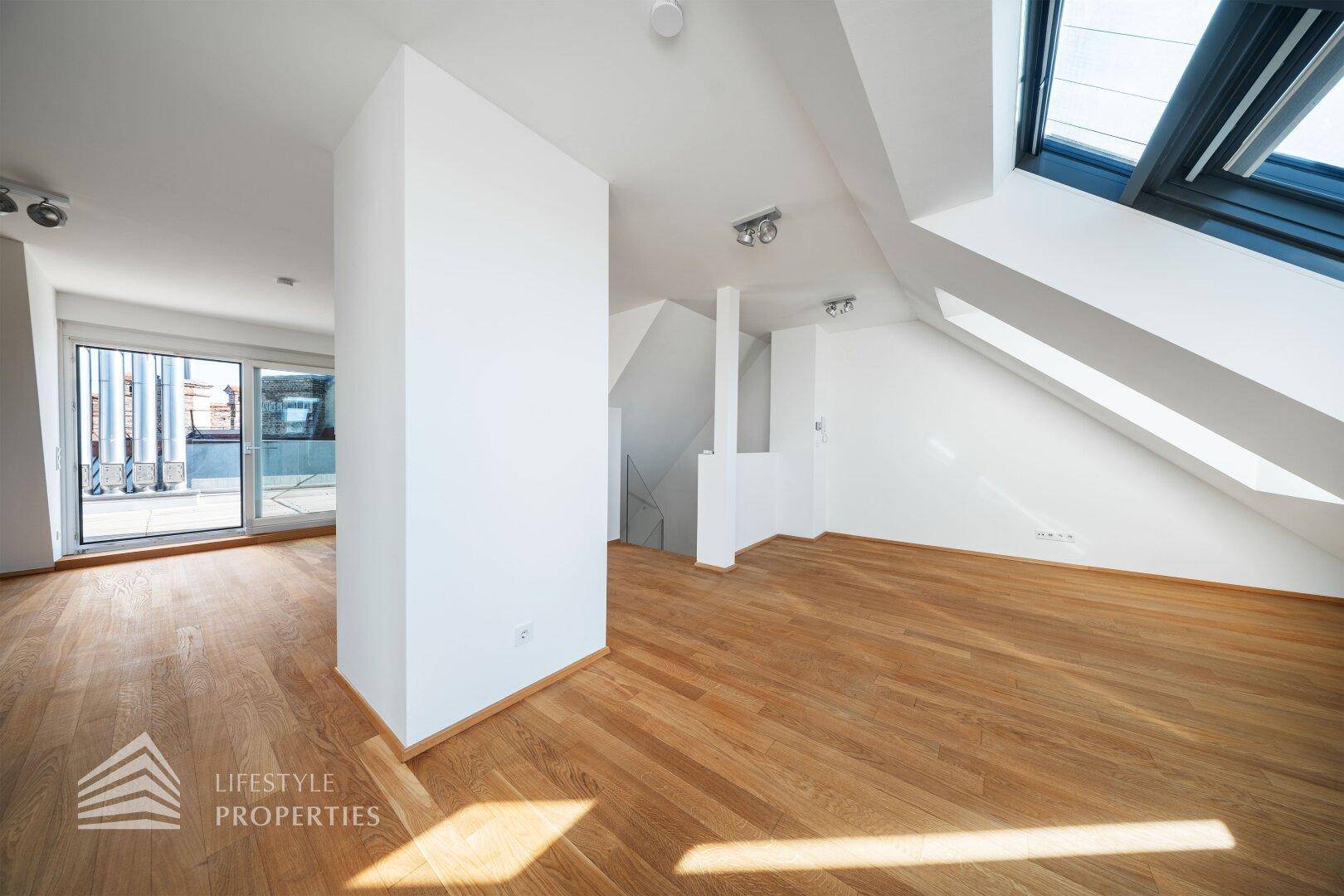 Offener Wohnbereich mit Holzboden, Säule und Zugang zu einer Dachterrasse.
