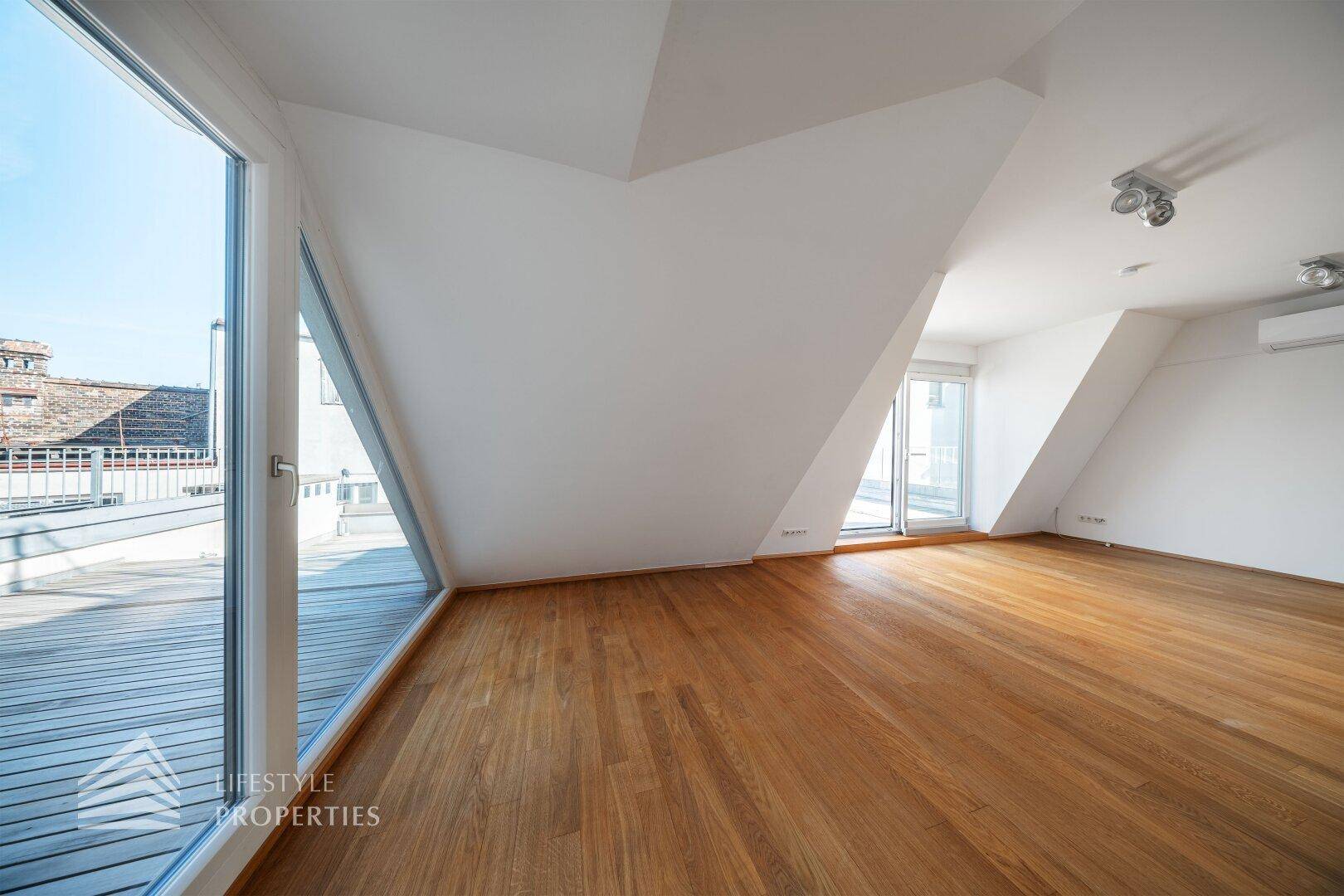 Geräumiger Wohnbereich mit Holzboden, großen Fenstern und Zugang zu einer Dachterrasse.