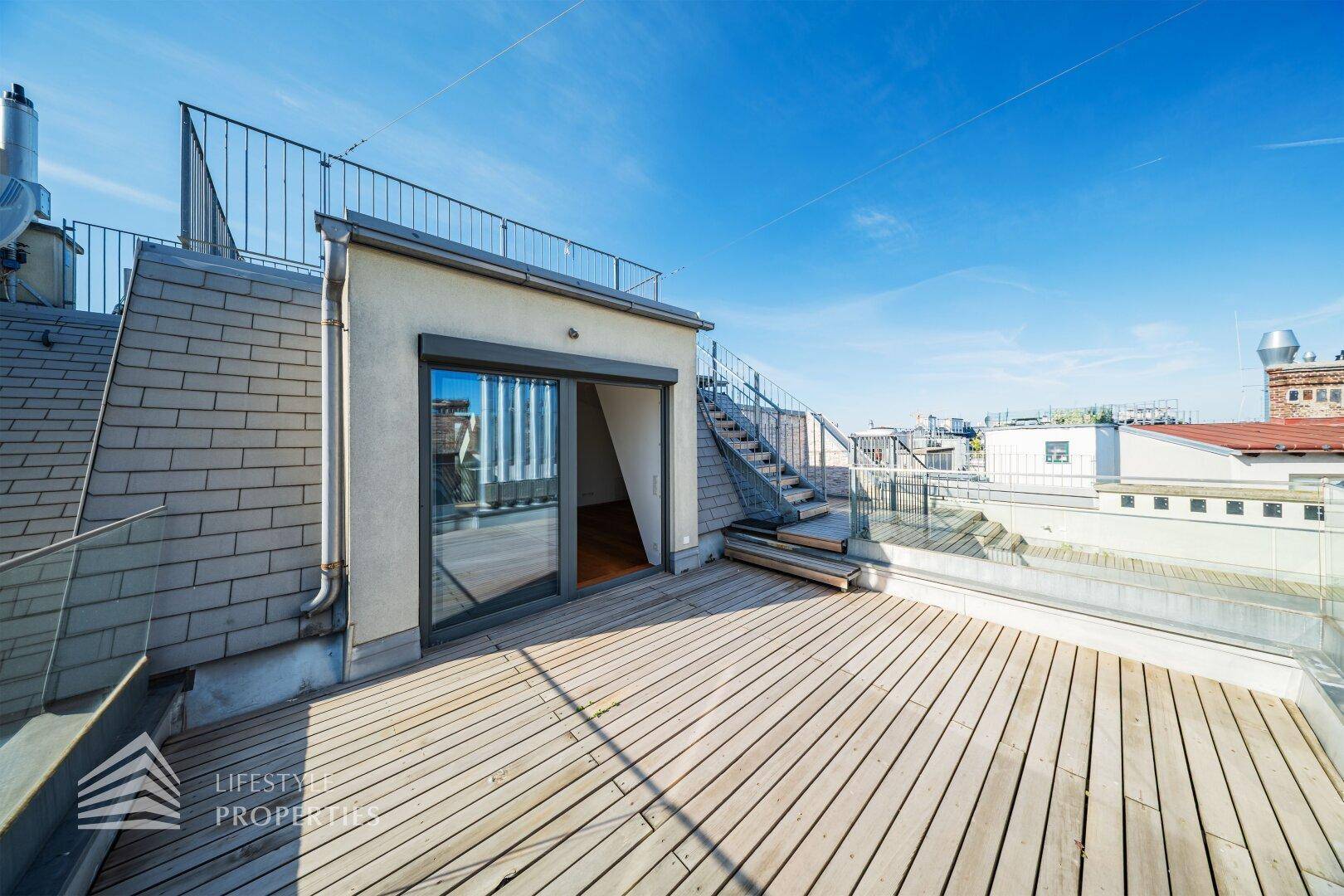 Große Dachterrasse mit Holzbelag, Metallgeländer und weitem Blick über die Stadt.