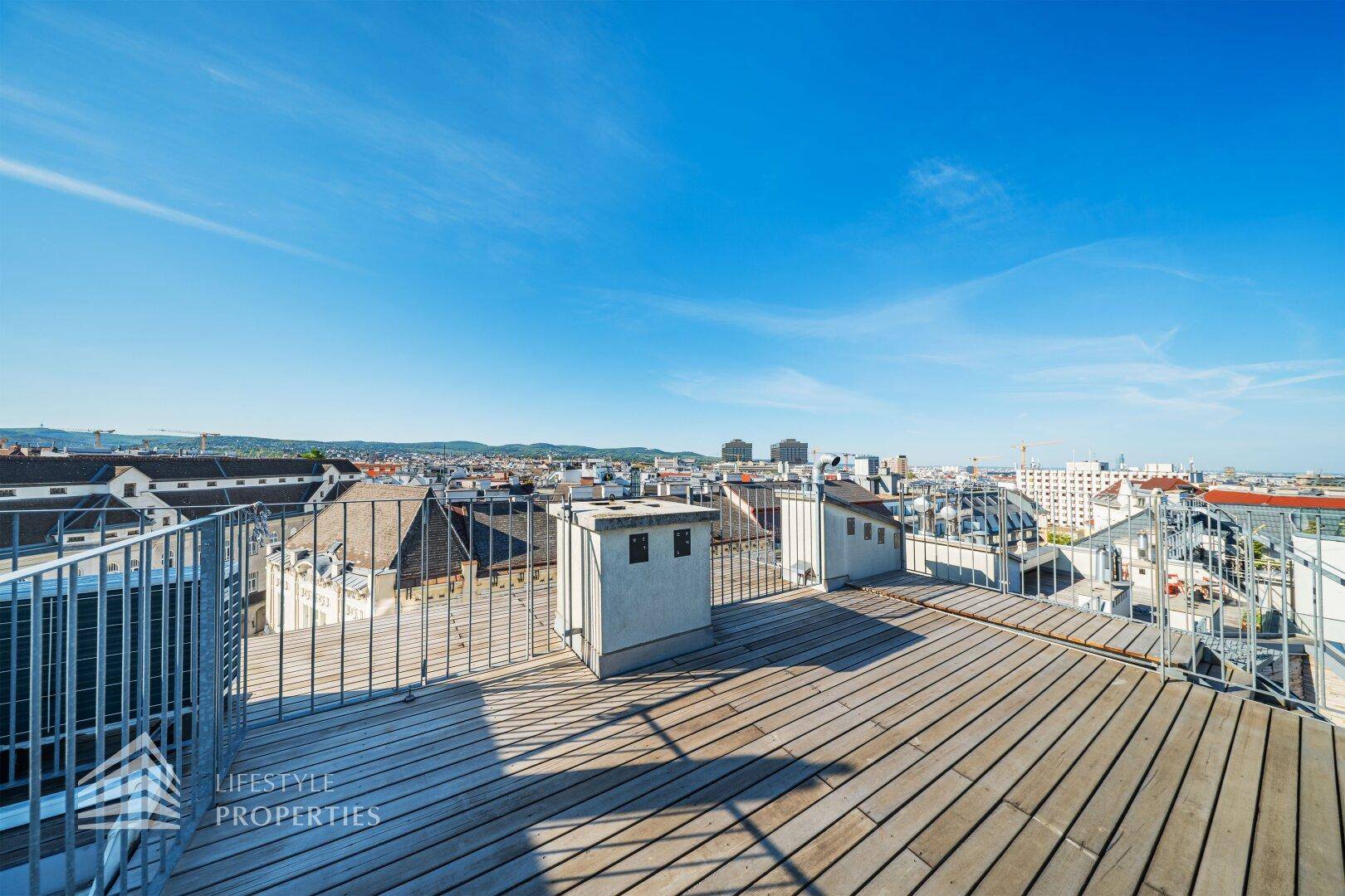 Offene Dachterrasse mit weitem Blick über die Dächer und die Skyline der Stadt.