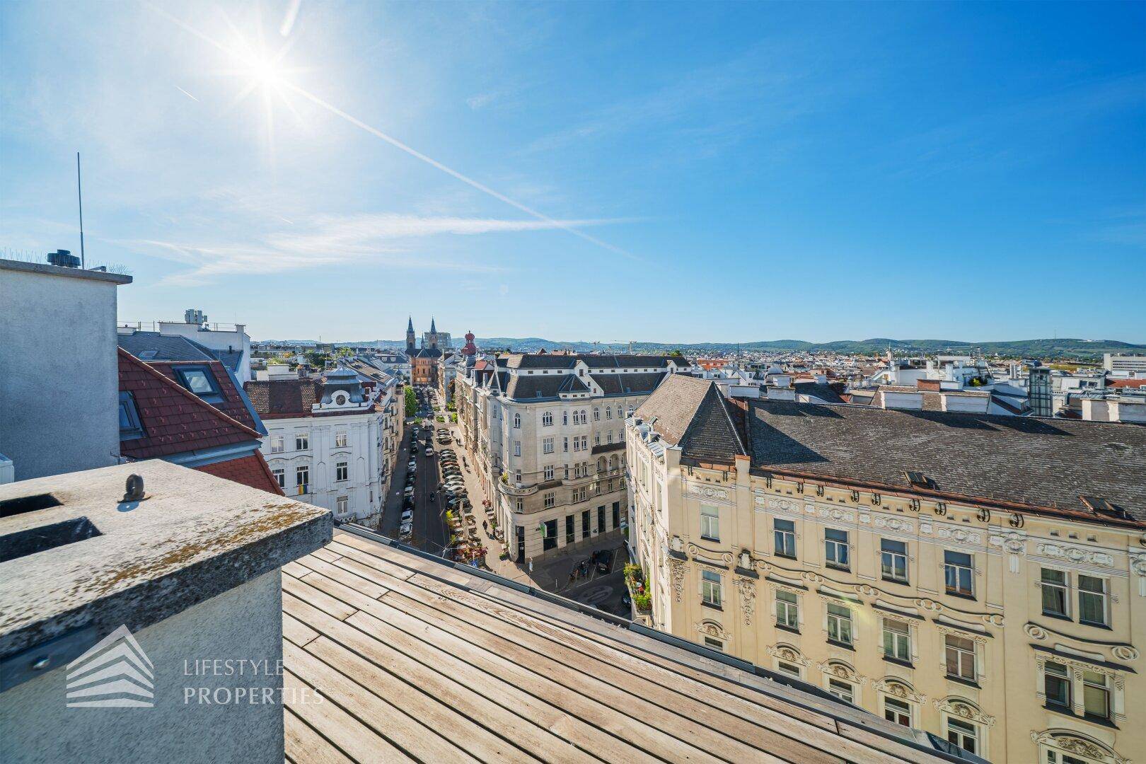 Weitläufiger Stadtblick von oben mit historischen Gebäuden und sonnigem Himmel.