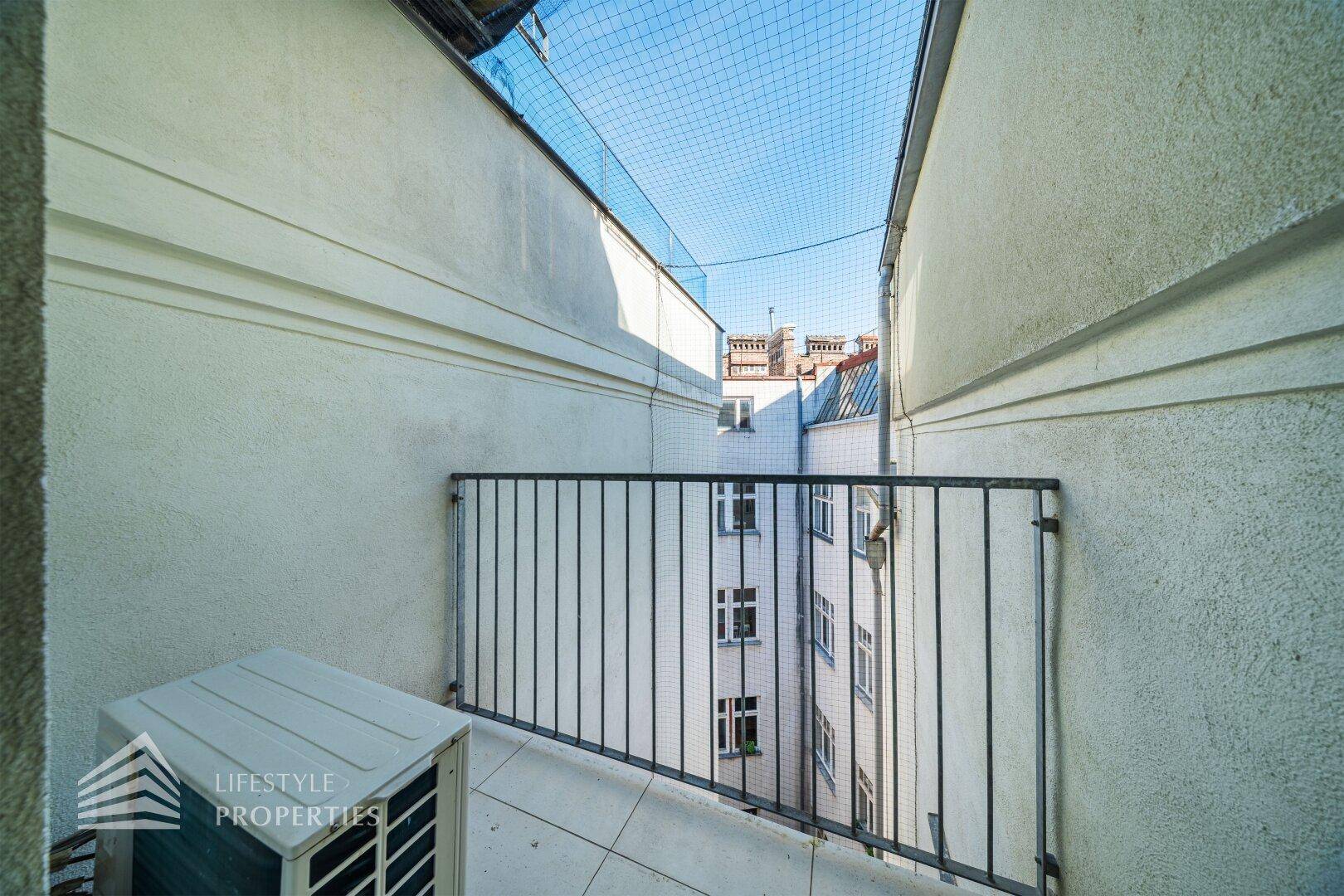 Kleiner Balkon mit Fliesenboden und Blick auf den Innenhof des Gebäudes.