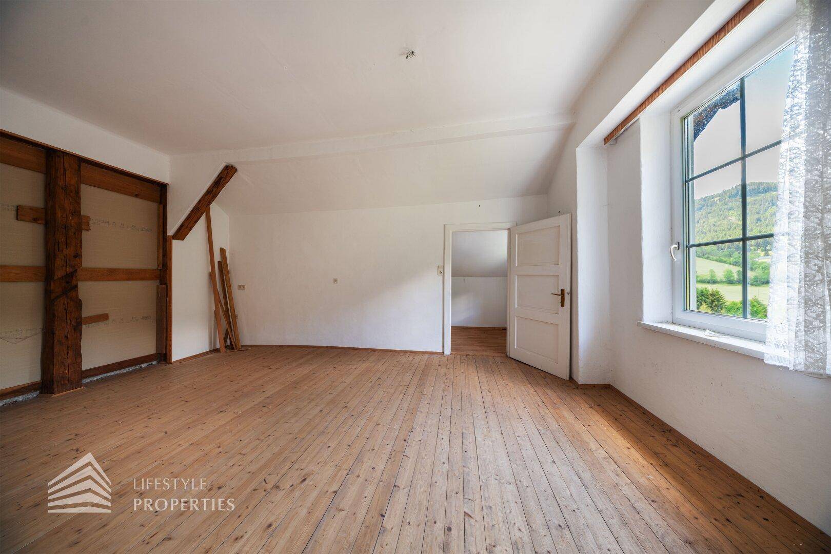Großes Wohnzimmer mit Holzdielenboden und freiliegenden Holzbalken, bereit zur individuellen Gestaltung.