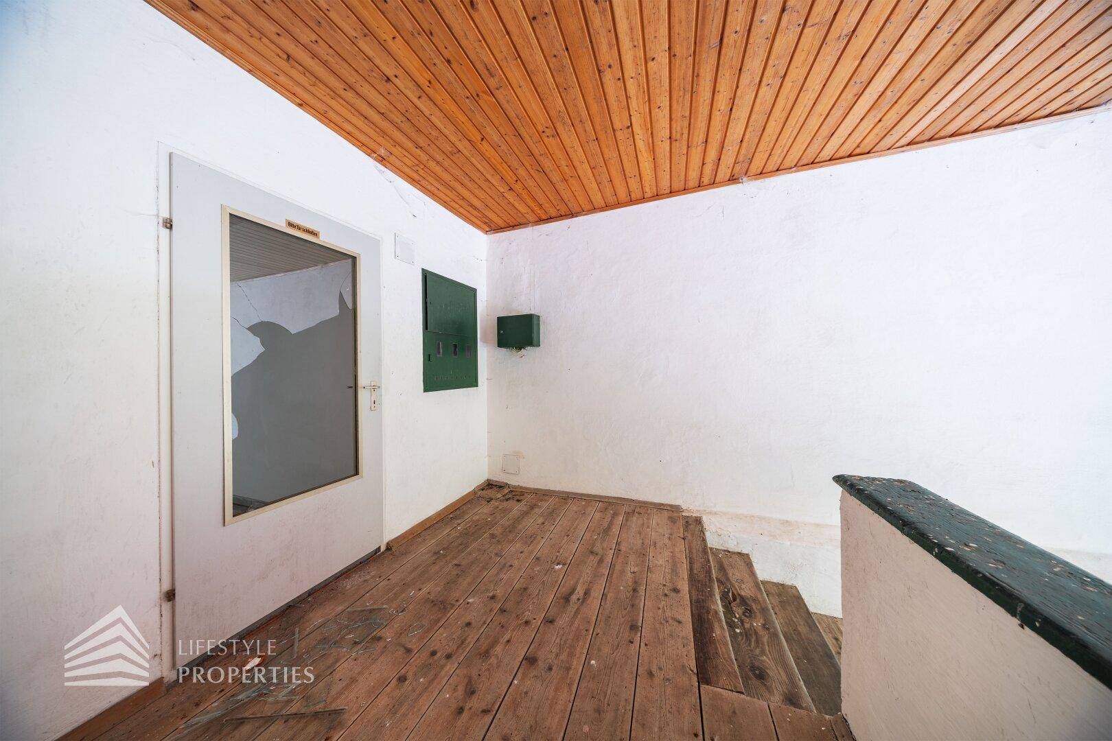 Eingangsbereich mit Treppe, Holzdielenboden und Holzdecke, hell und einladend.