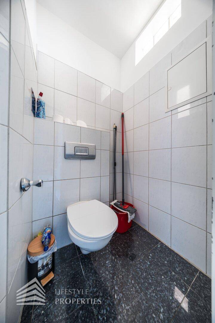 Einfaches Gäste-WC mit Wand-WC und hellen Fliesen, funktional und sauber.