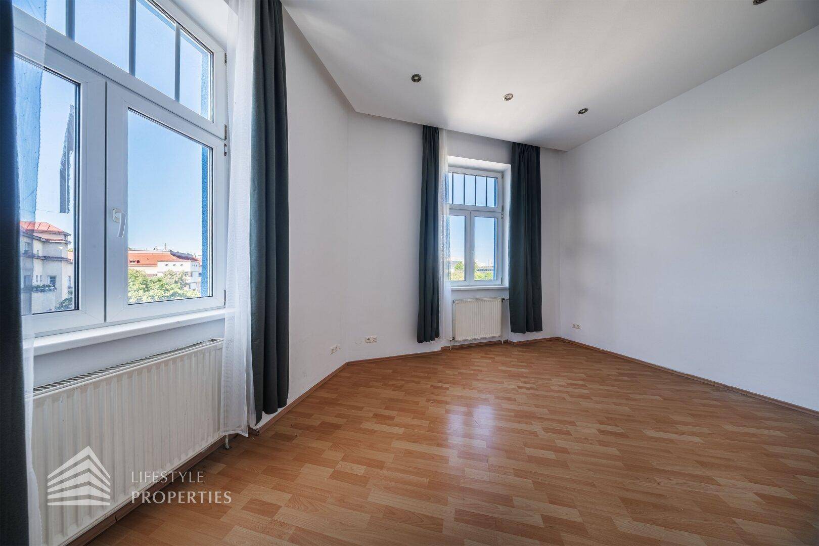 Geräumiges Zimmer mit Holzboden und Fenstern, die einen Blick auf die Umgebung bieten.