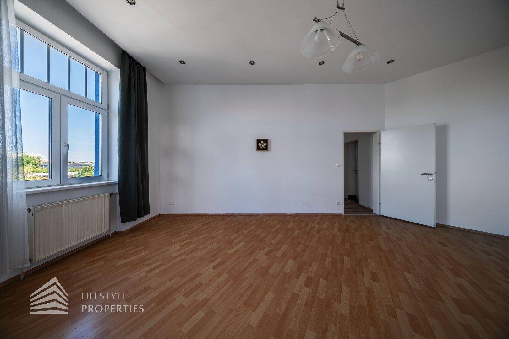 Heller Wohnbereich mit Parkettboden und großen Fenstern, die für eine angenehme Atmosphäre sorgen.