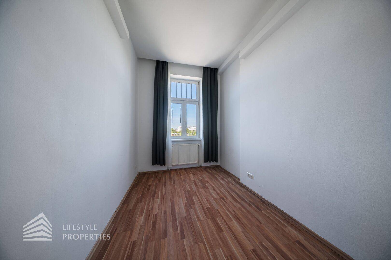 Kleineres Zimmer mit Parkettboden und einem Fenster, ideal als Schlaf- oder Arbeitszimmer.