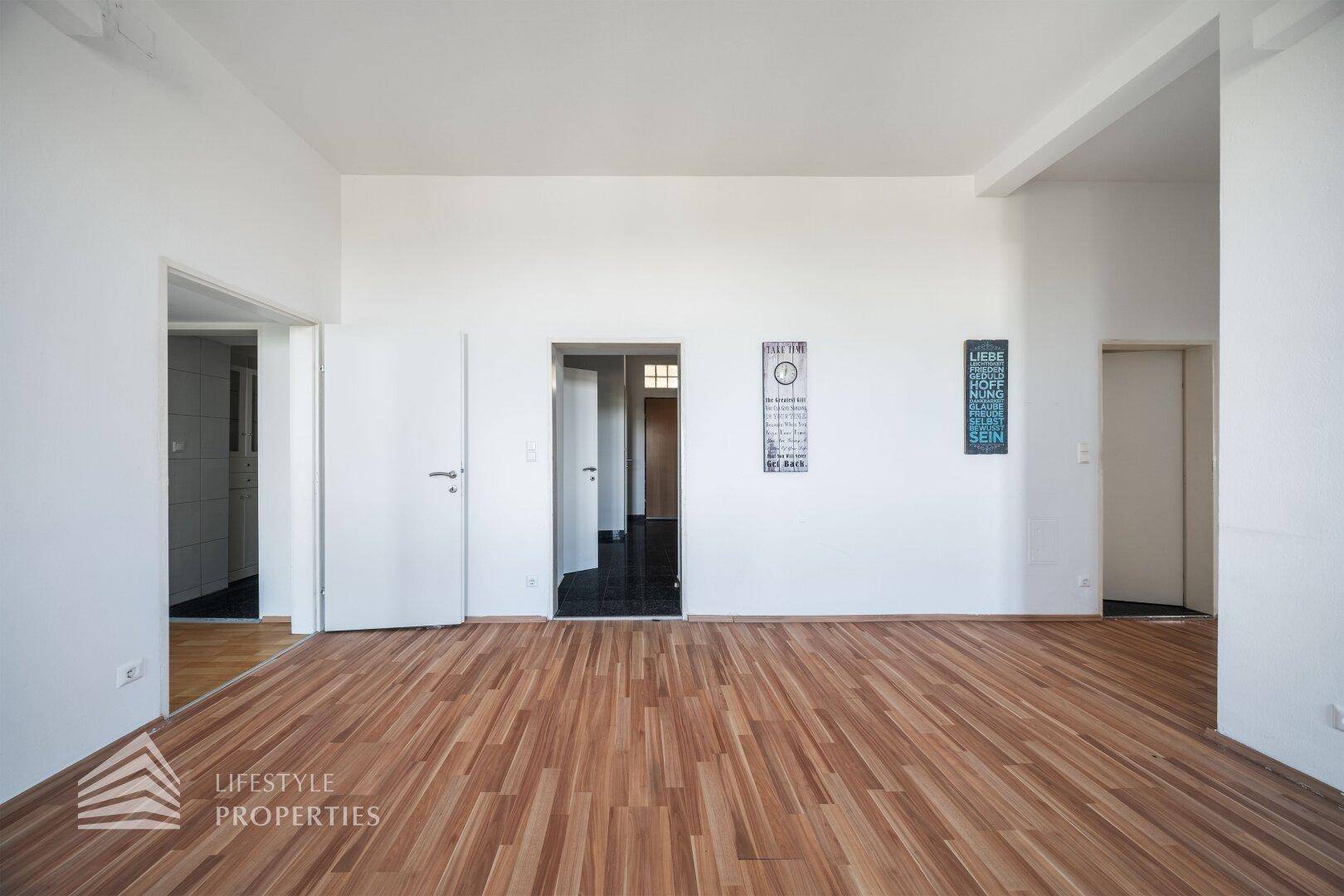 Heller Wohnbereich mit Parkettboden und Zugang zu weiteren Räumen der Wohnung.