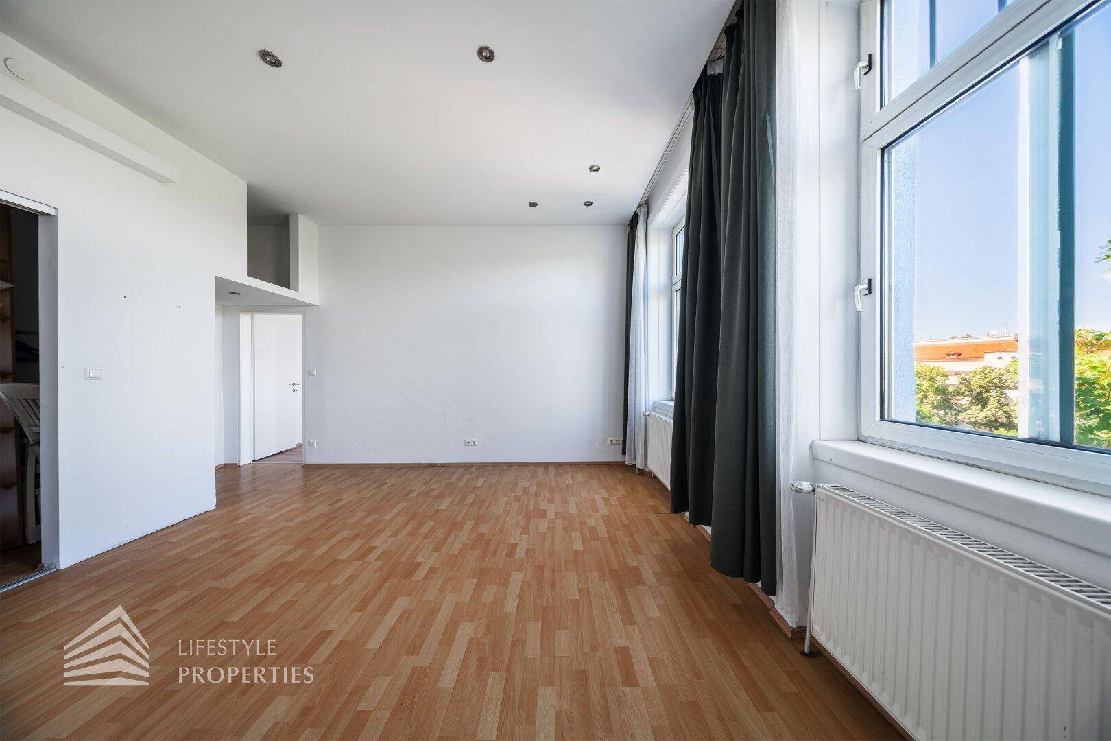 Helles Zimmer mit Parkettboden und Fenstern, die viel Tageslicht in den Raum lassen.