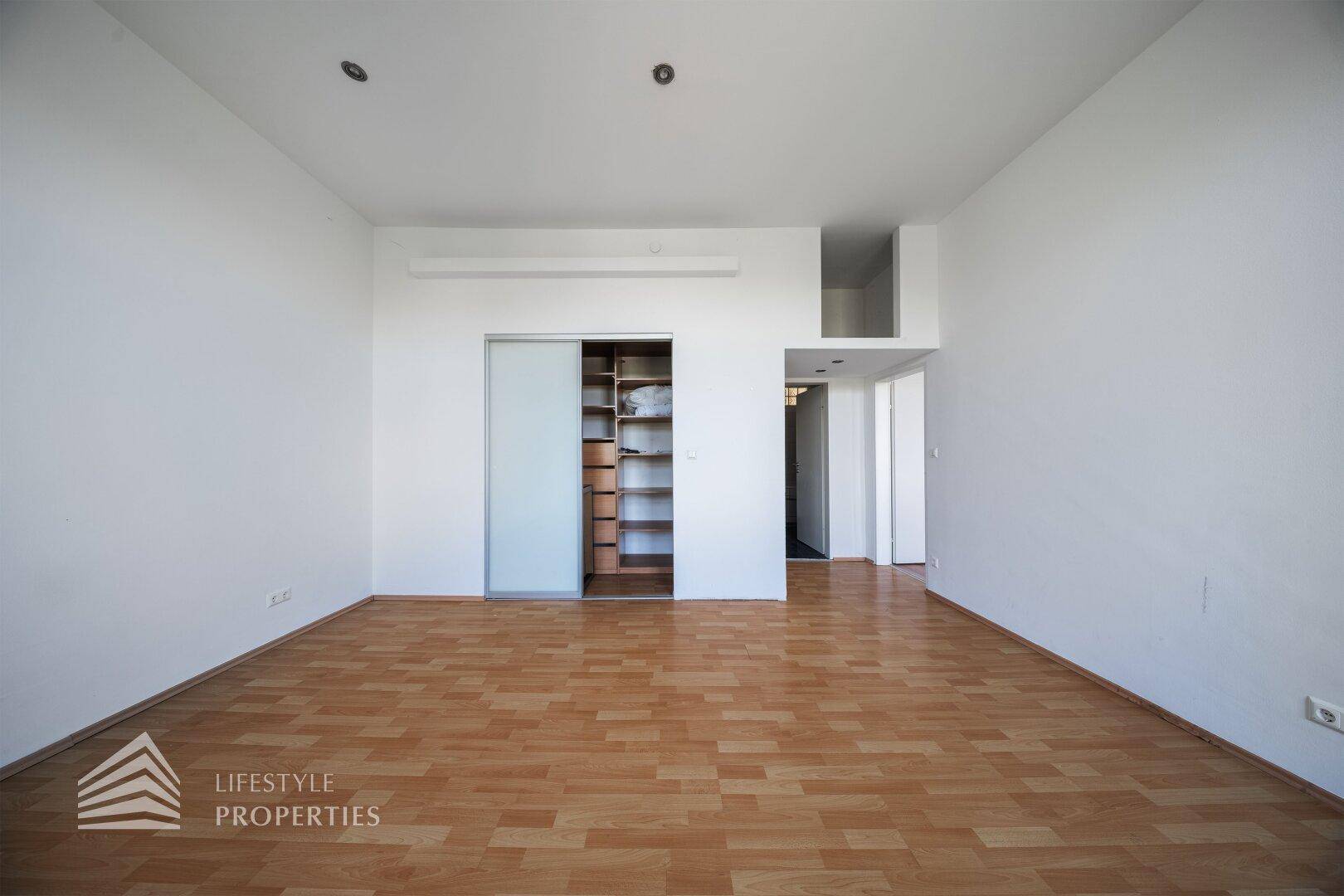 Zimmer mit Parkettboden und einem großen Einbauschrank mit Schiebetüren.