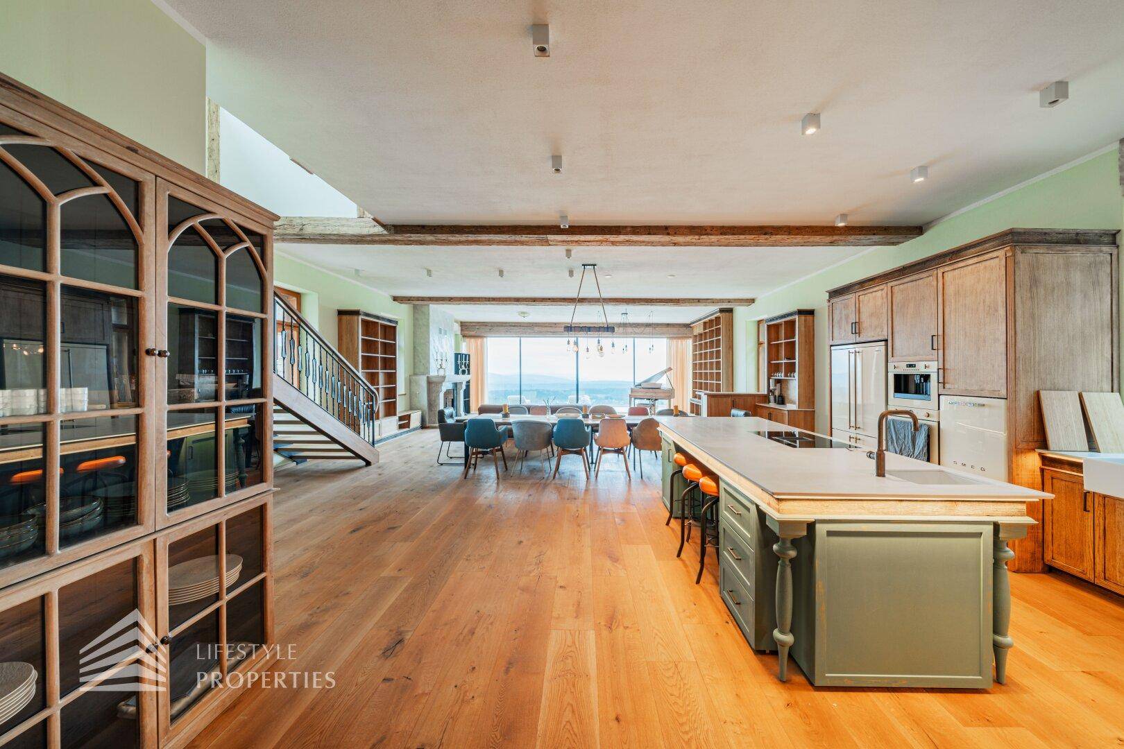 Geräumige Küche mit Insel und Essbereich, offen zum Wohnzimmer mit Panoramafenstern.