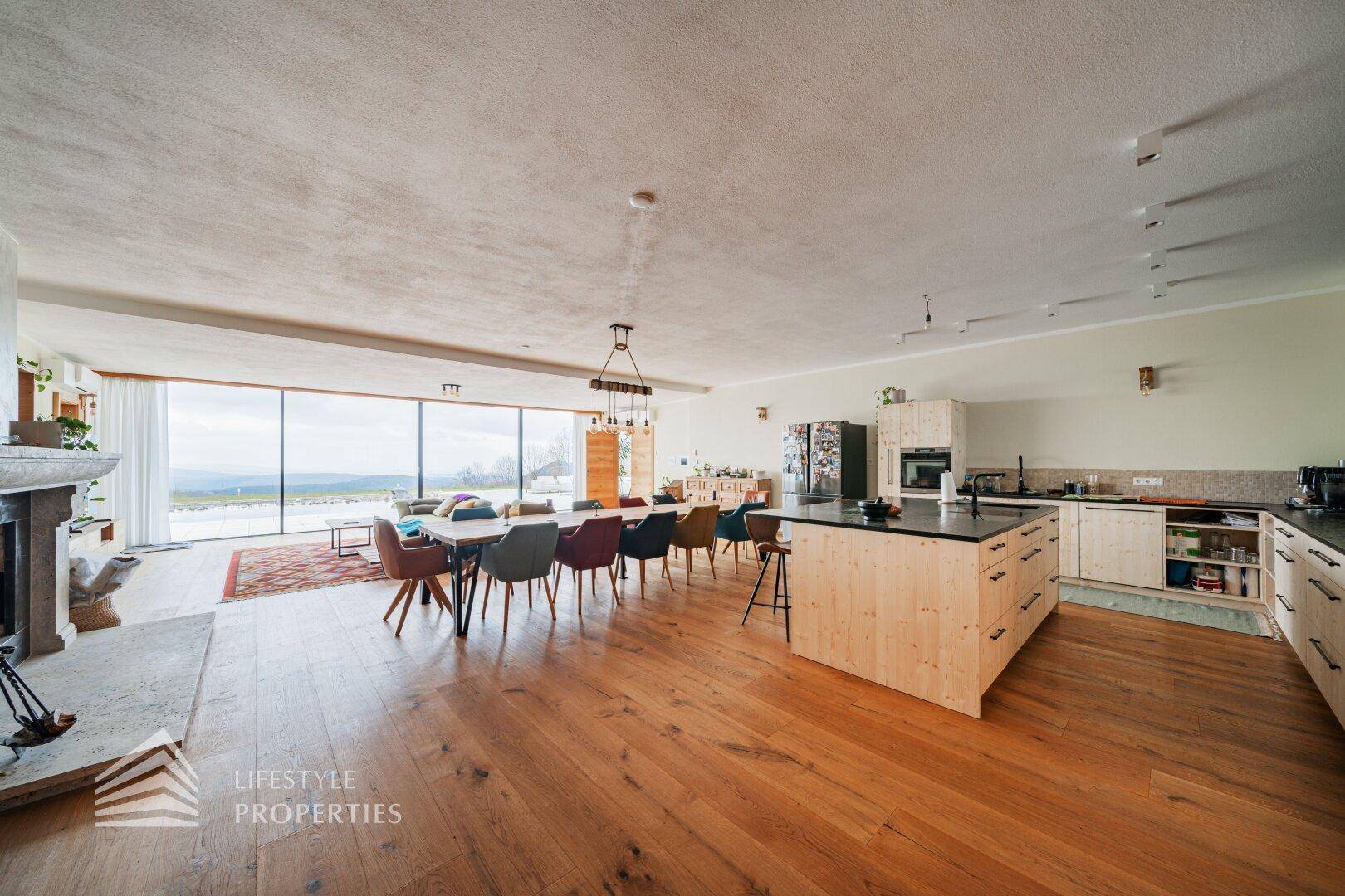 Offener Wohnbereich mit Holzboden, Kamin und moderner Küche mit Insel und Essbereich.