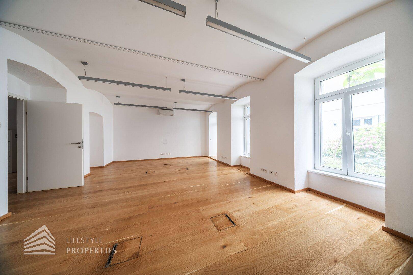 Heller, leerer Raum mit Holzboden und gewölbten Fenstern, bereit für individuelle Gestaltung.