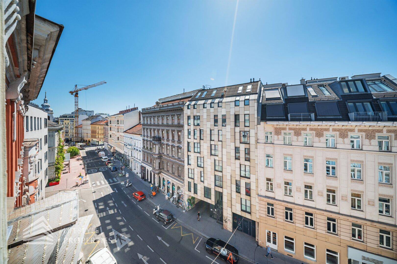 Panoramablick auf eine belebte Stadtstraße mit historischen und modernen Gebäuden.