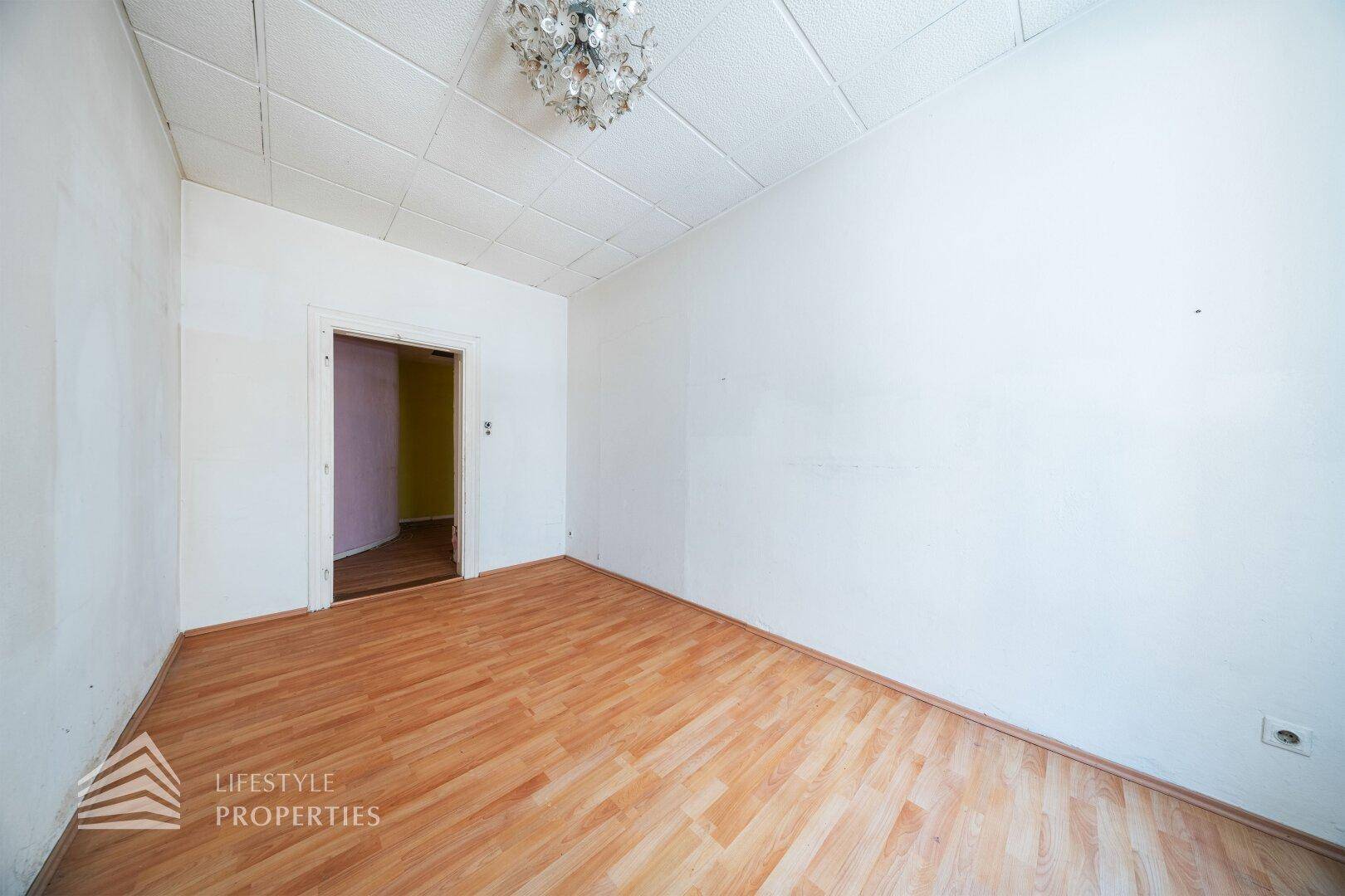 Leerer Raum mit Laminatboden und Zugang zu einem weiteren Zimmer.