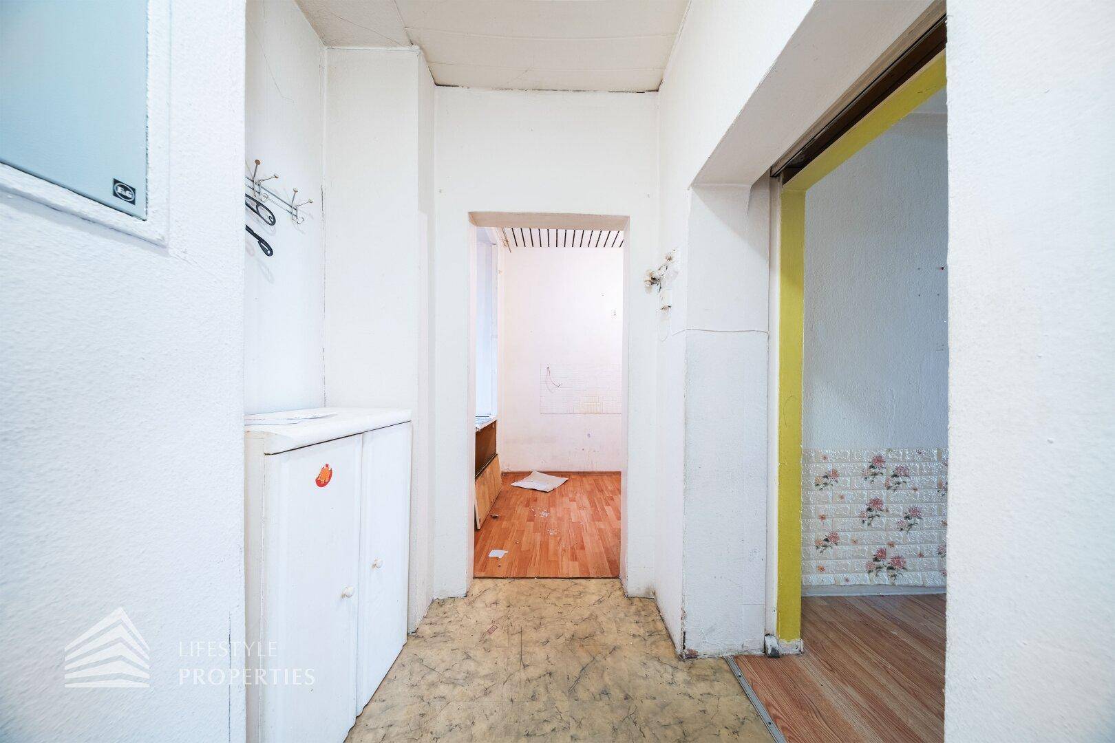 Flur mit Linoleumboden und Durchgang zu einem weiteren Zimmer.