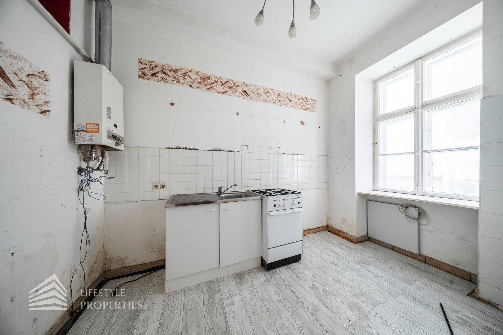 Renovierungsbedürftige Küche mit Gastherme, Spüle und Herd, bietet Potenzial für eine moderne Gestaltung.