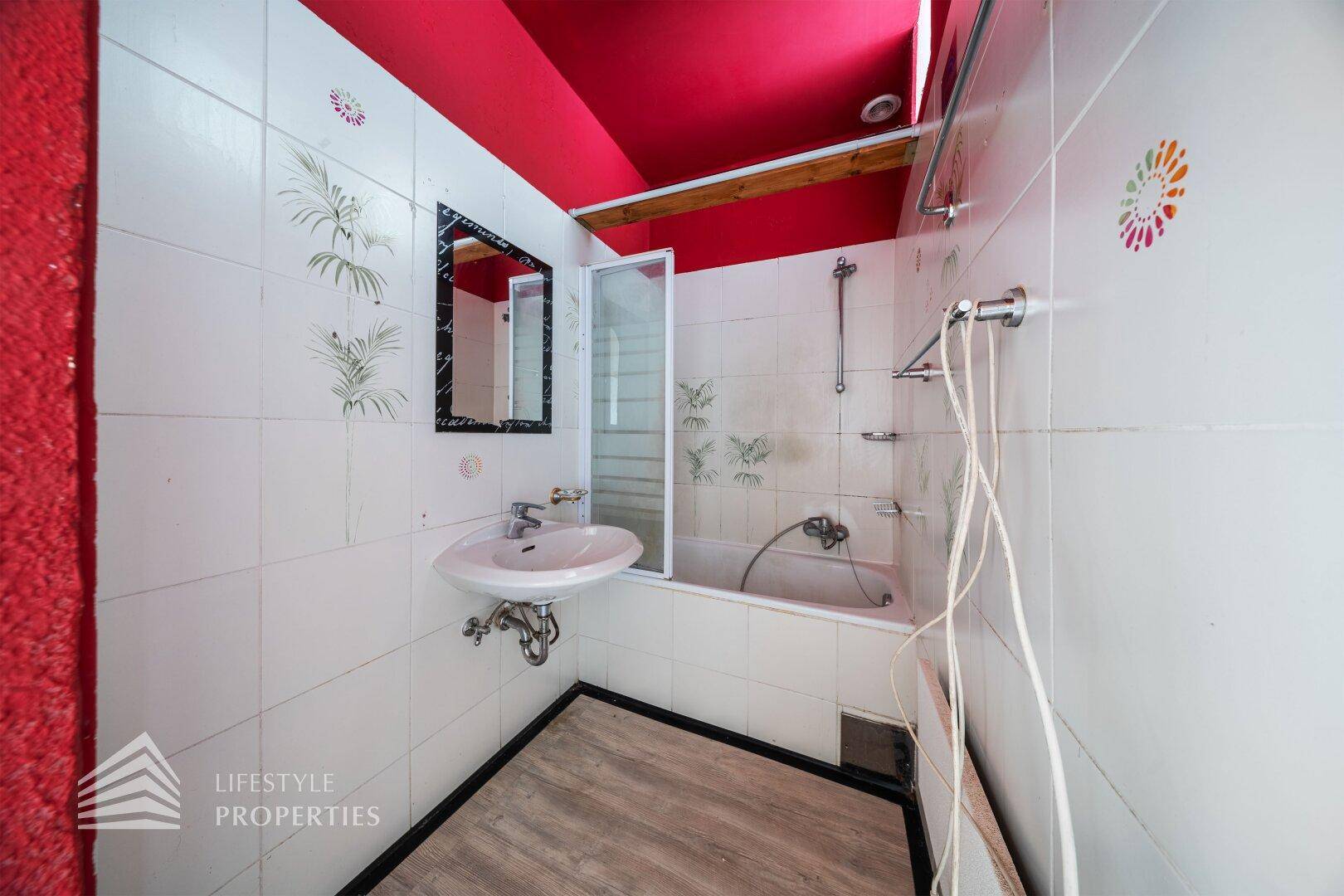 Badezimmer mit Badewanne, Waschbecken und Fliesen, benötigt eine Modernisierung.