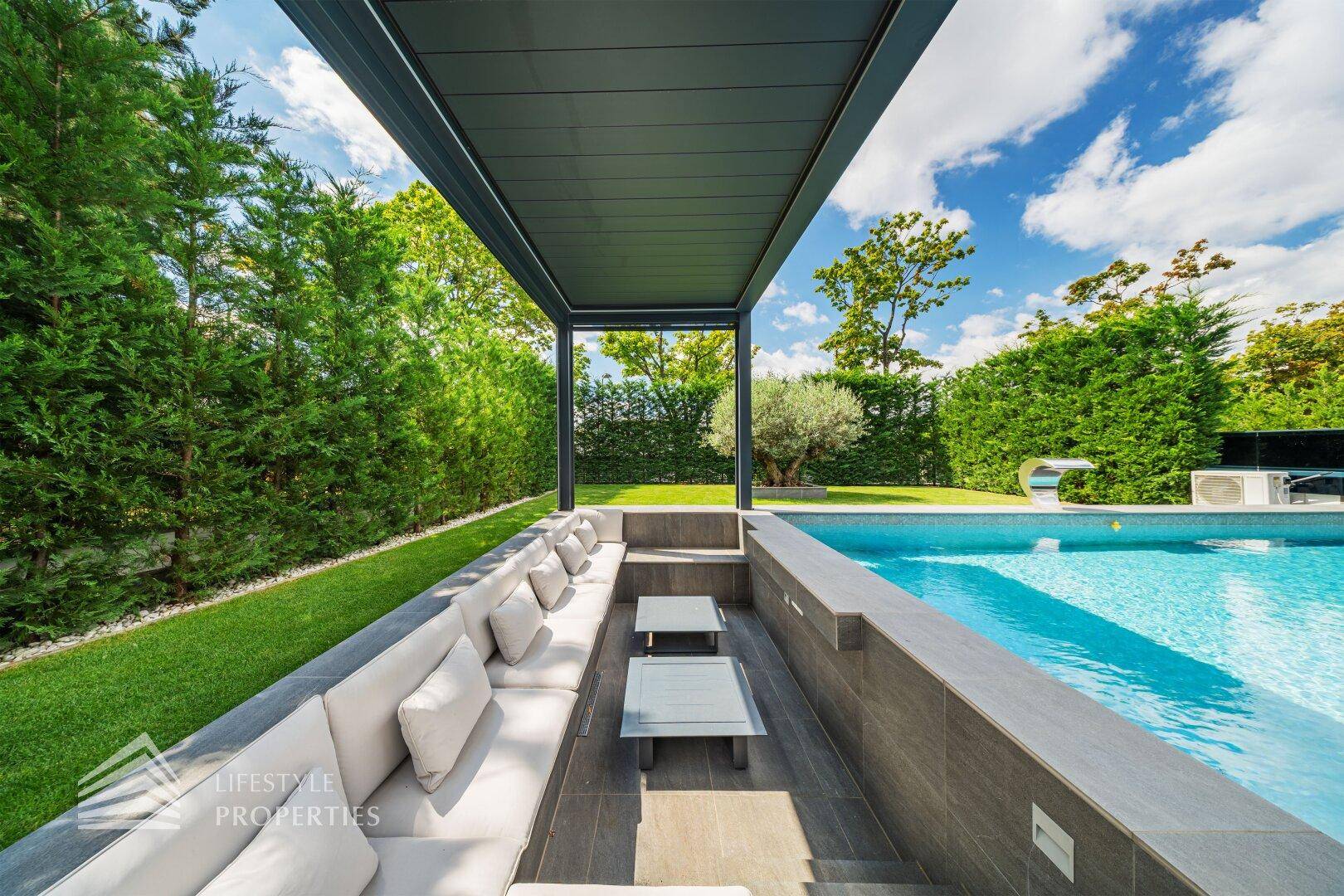 Gemütlicher, eingelassener Lounge-Bereich unter einer modernen Pergola, ideal zum Entspannen im Freien.