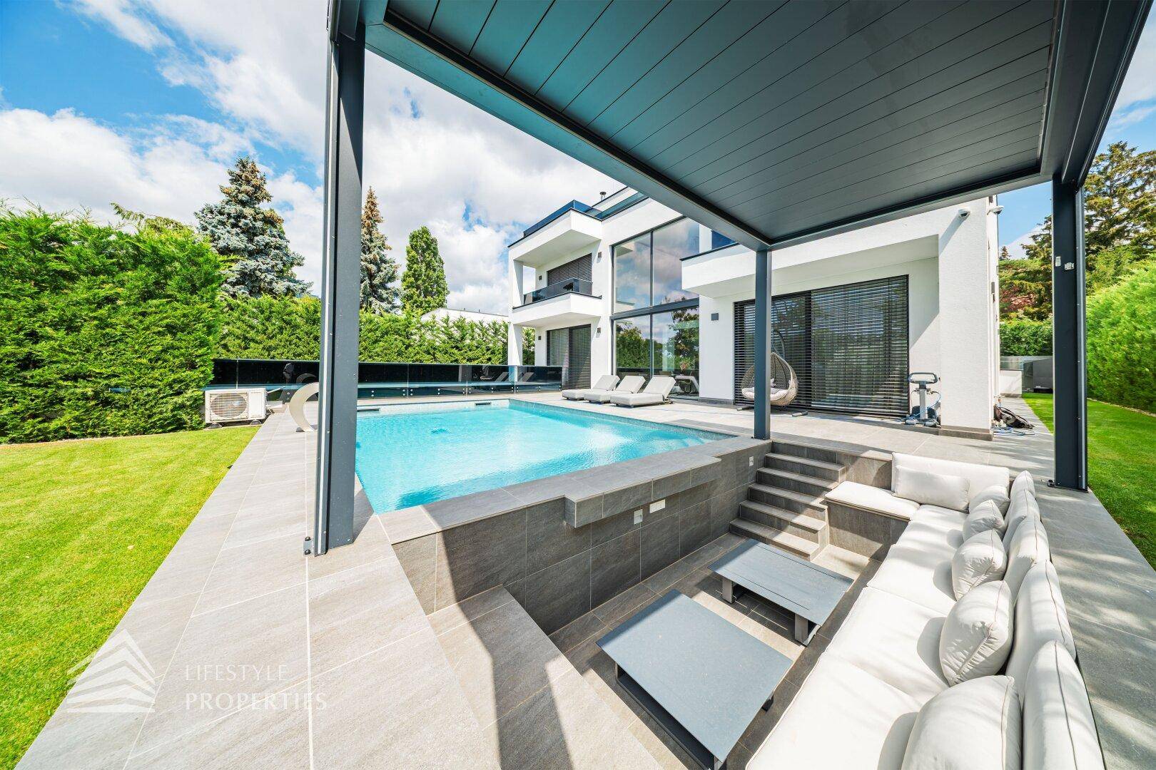 Luxuriöser Außenbereich mit Pool, eingelassenem Lounge-Bereich unter einer Pergola und gepflegtem Rasen.