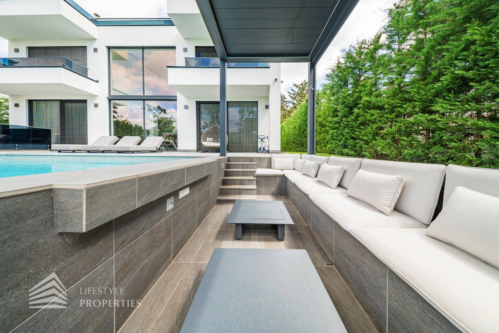 Moderner, eingelassener Lounge-Bereich mit bequemen Sitzgelegenheiten und Blick auf den Pool.