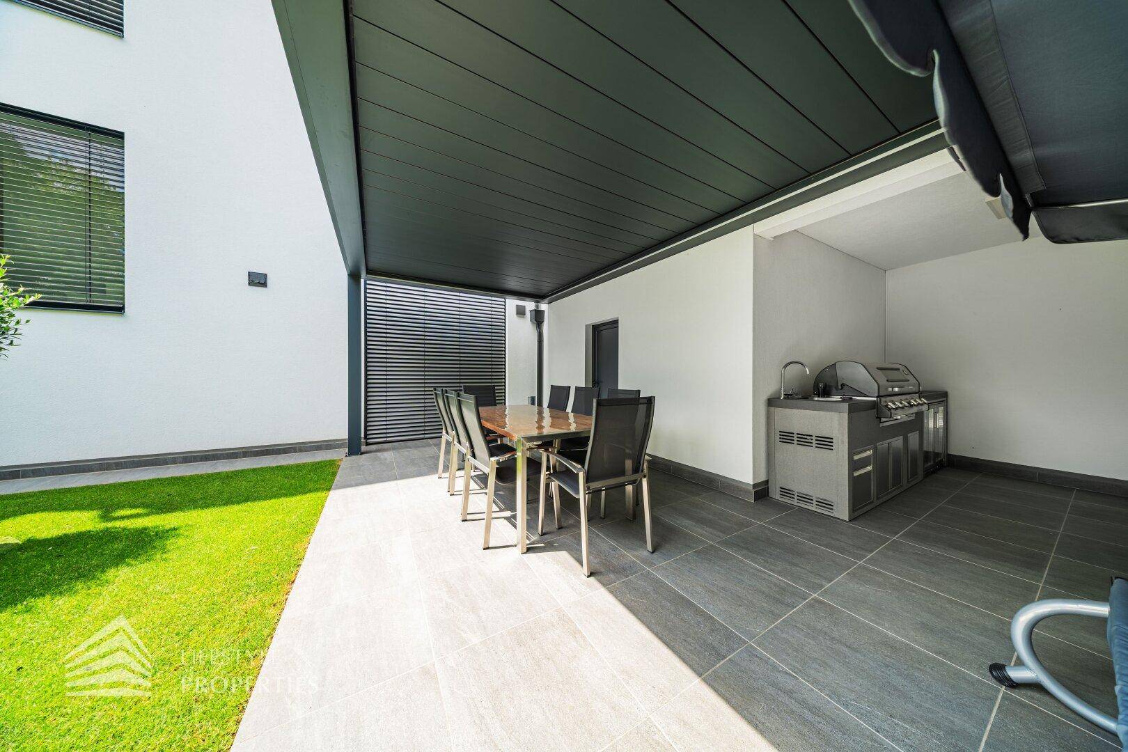 Überdachte Terrasse mit Essbereich und einer voll ausgestatteten Außenküche für gesellige Abende.