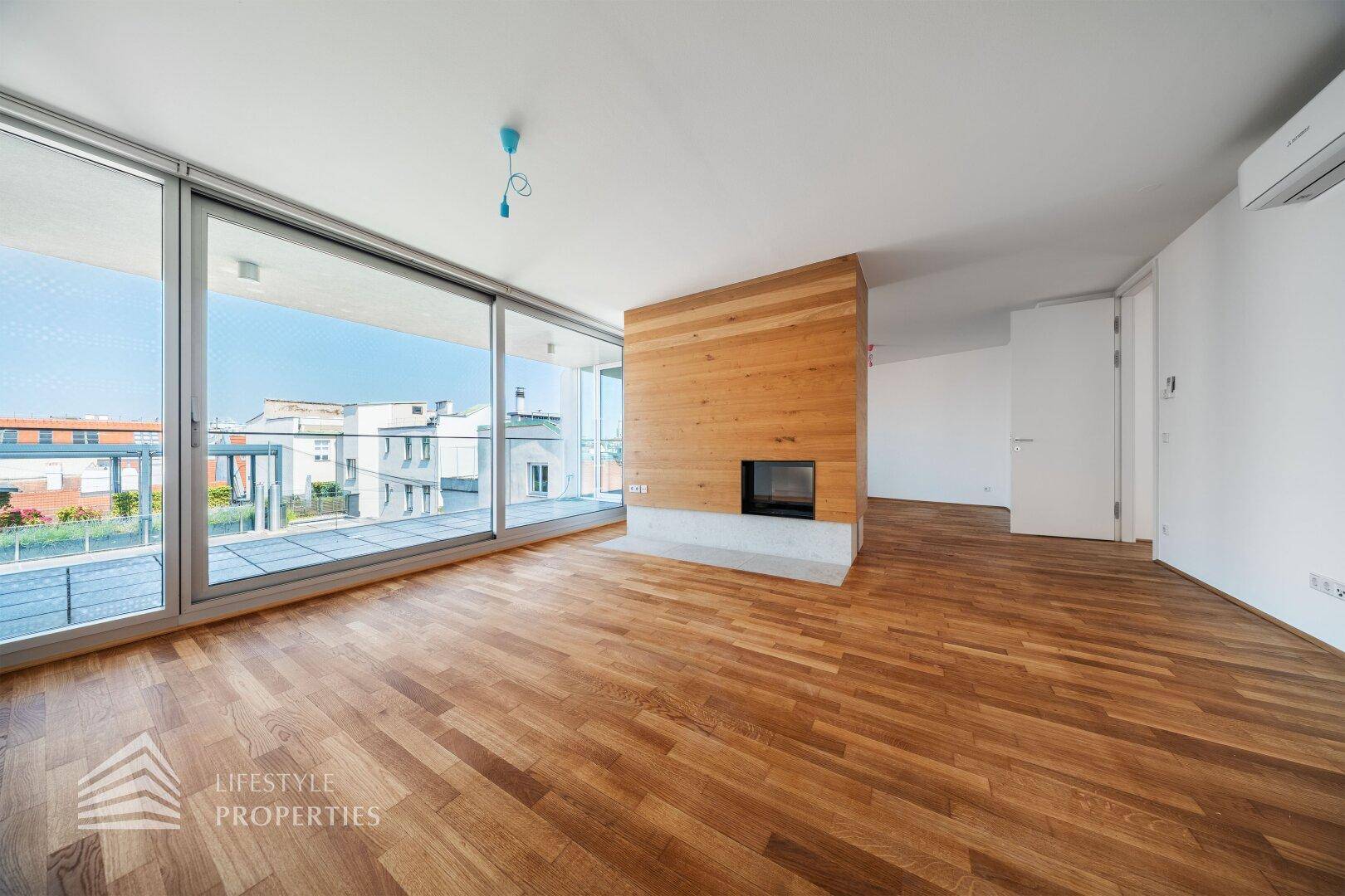 Lichtdurchflutetes Wohnzimmer mit Holzboden, Holzkaminwand und bodentiefen Fenstern.