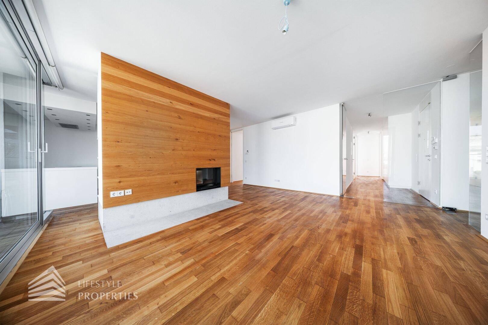 Geräumiges Wohnzimmer mit Holzboden, Akzentwand aus Holz und modernem Kamin.