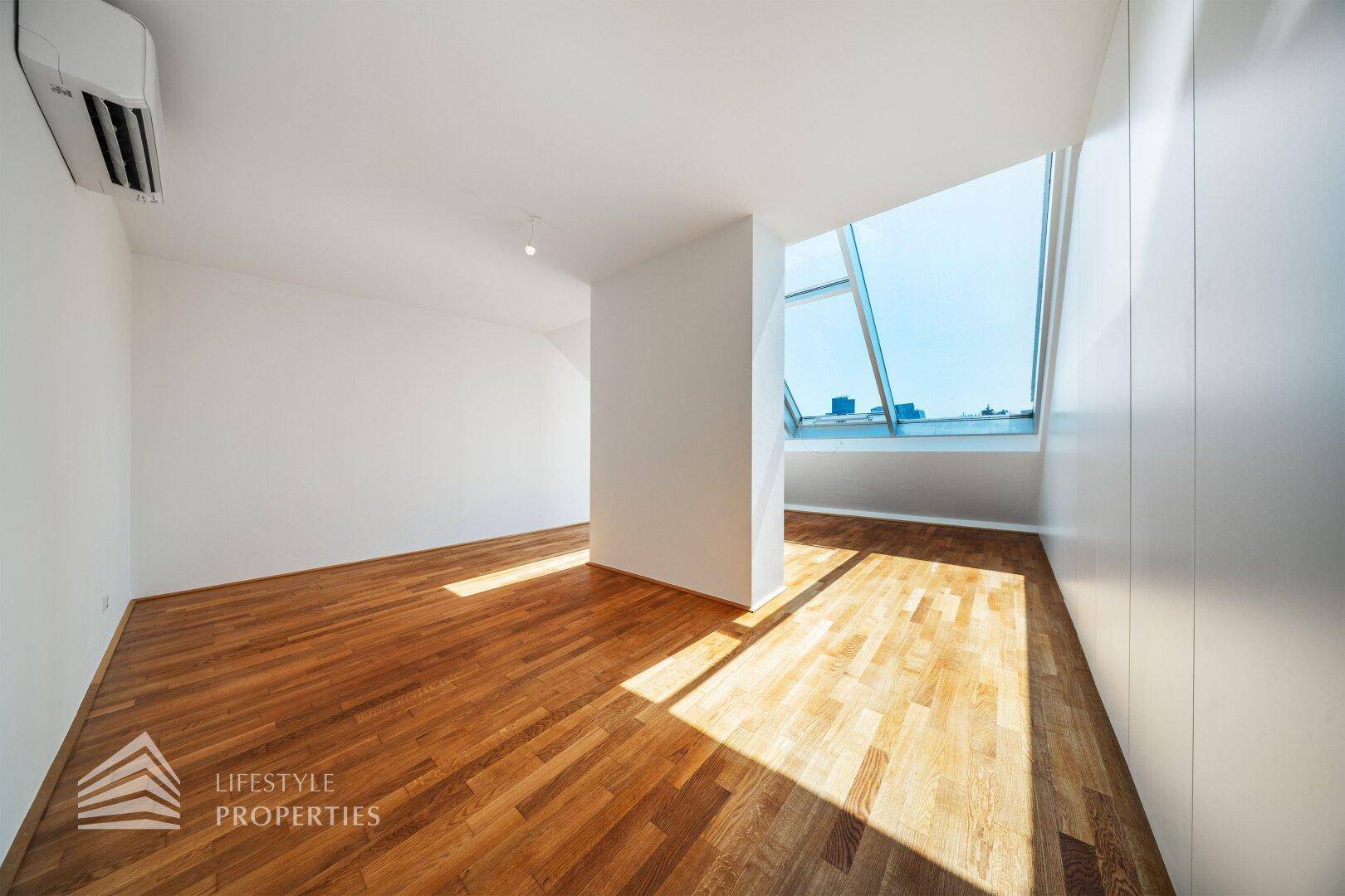 Dachgeschosszimmer mit Holzboden, Einbauschränken und großen Dachfenstern für viel Licht.