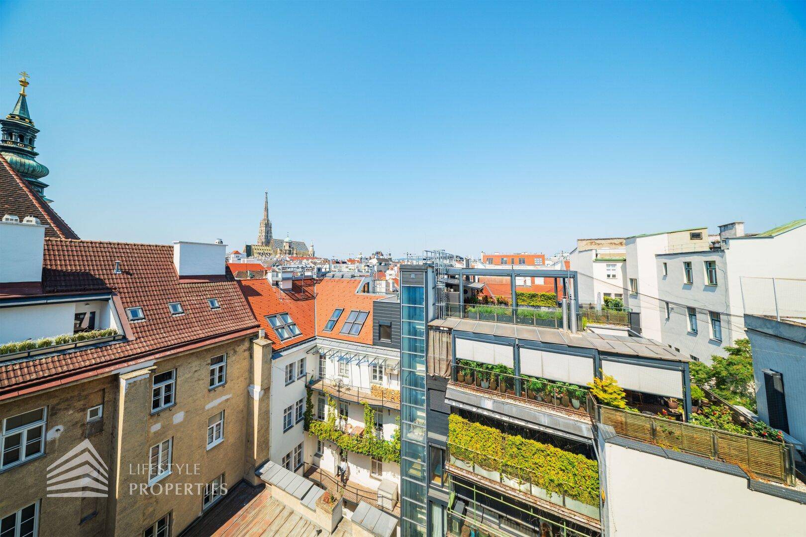 Panoramablick über die Dächer der Stadt mit historischen Gebäuden und einem Kirchturm.