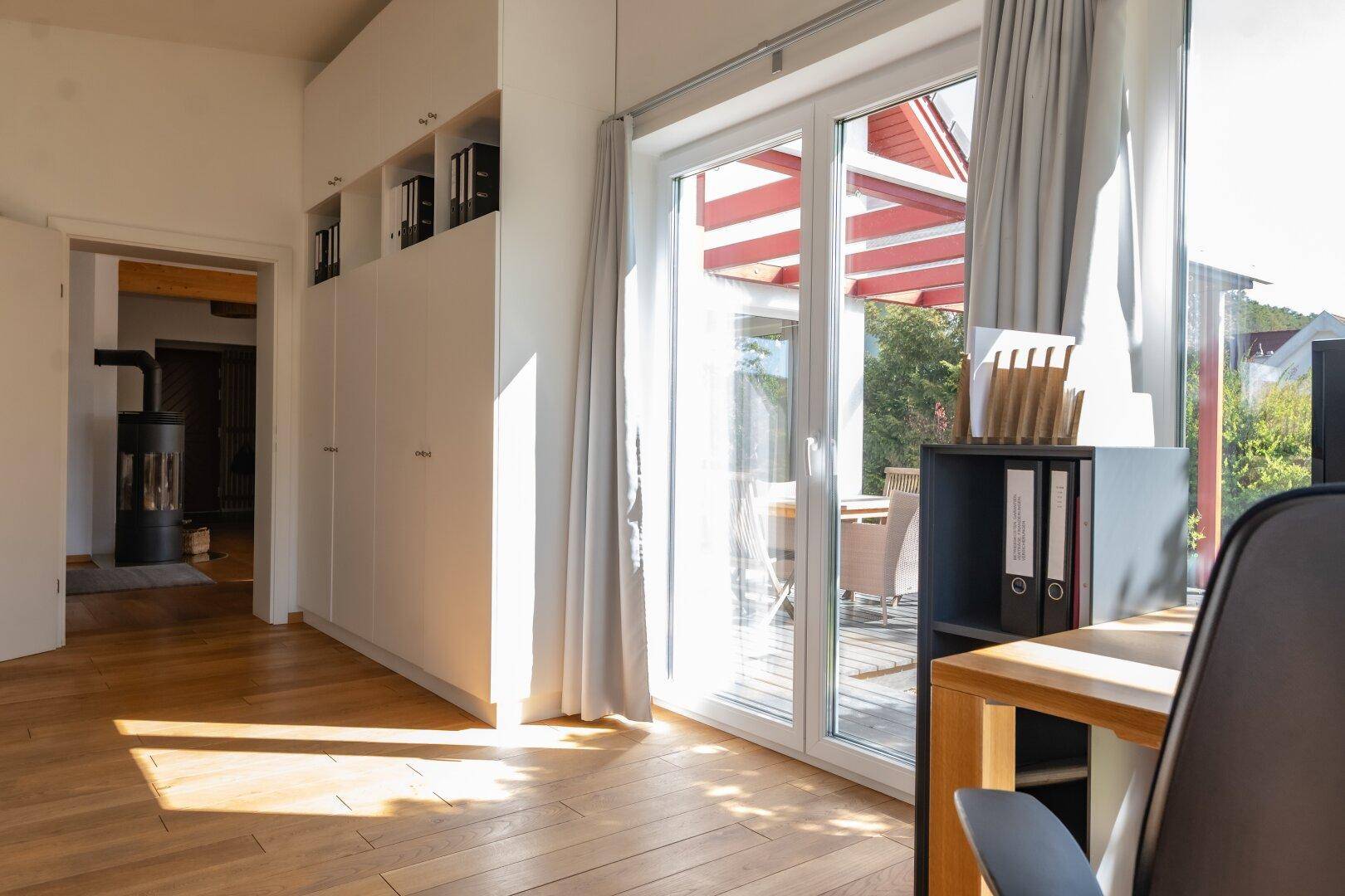 Heller Flur mit Einbauschränken und Zugang zu einer überdachten Terrasse.