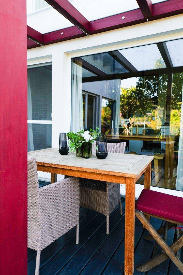 Gemütliche überdachte Terrasse mit Esstisch und Stühlen für Mahlzeiten im Freien.